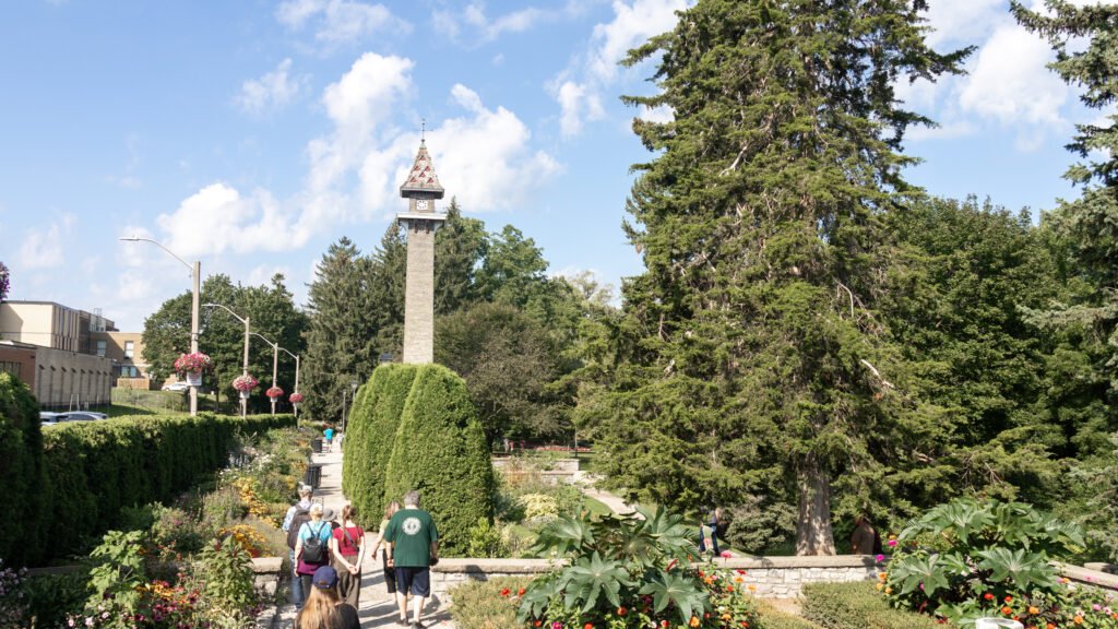 Shakespearean Gardens Stratford | Krista the Explorer Group of people walking along a garden path toward a tall clock tower.