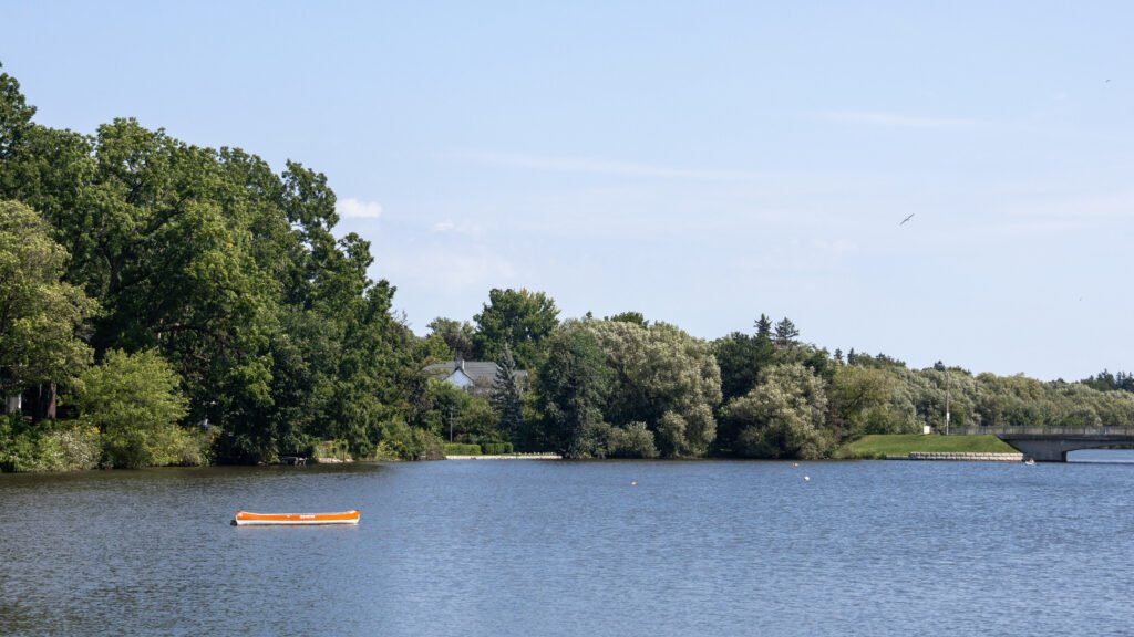 Boat Stratford | Krista the Explorer Quiet lake scene with a small orange canoe near the shore.