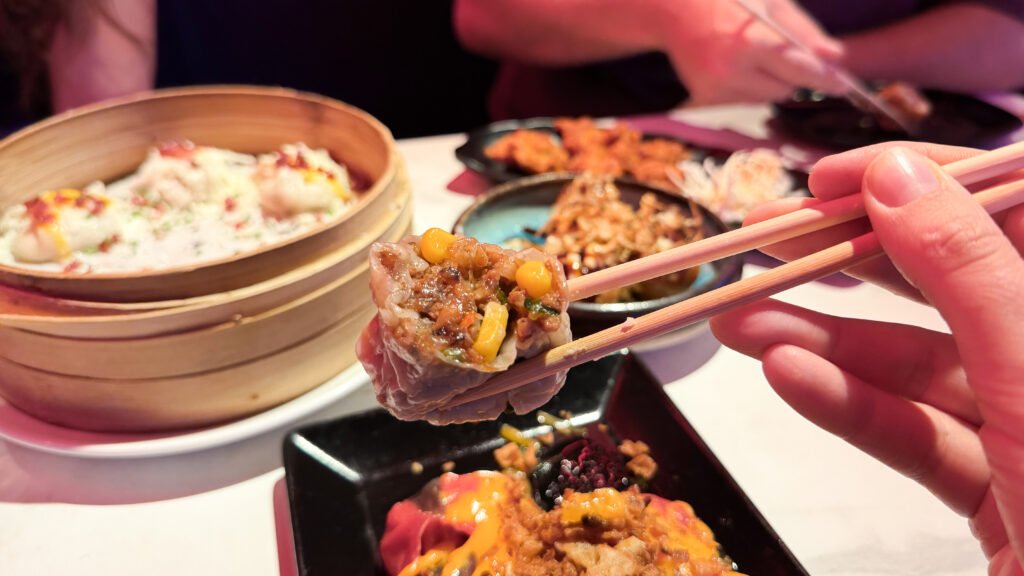 Chun-Li Dumplings Malaga | Krista the Explorer Close-up of a bite-sized dumpling filled with corn and vegetables with other dishes on table.