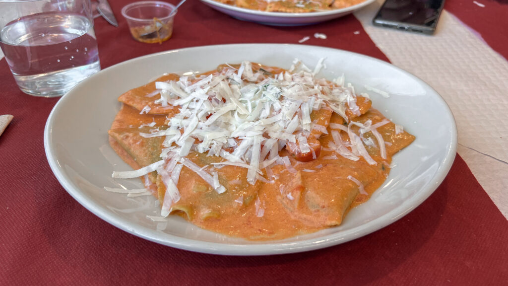 Plate of pasta covered in orange sauce and grated cheese.