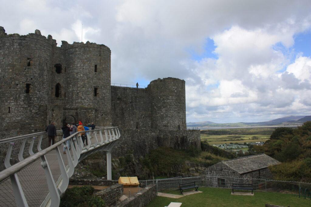 Long modern bridge leading to castle in Wales.