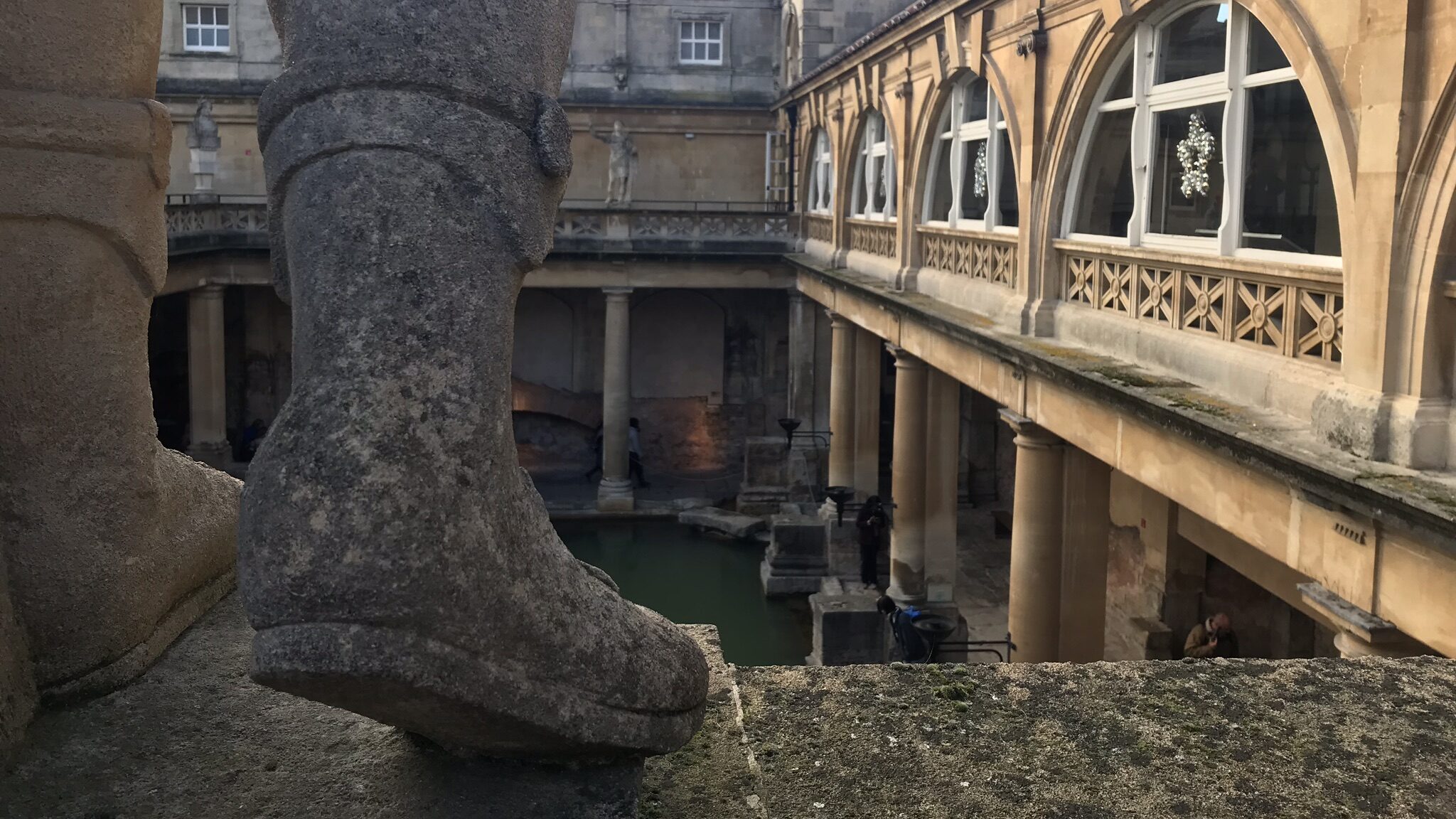 Foot of statue on ledge in Roman Baths.