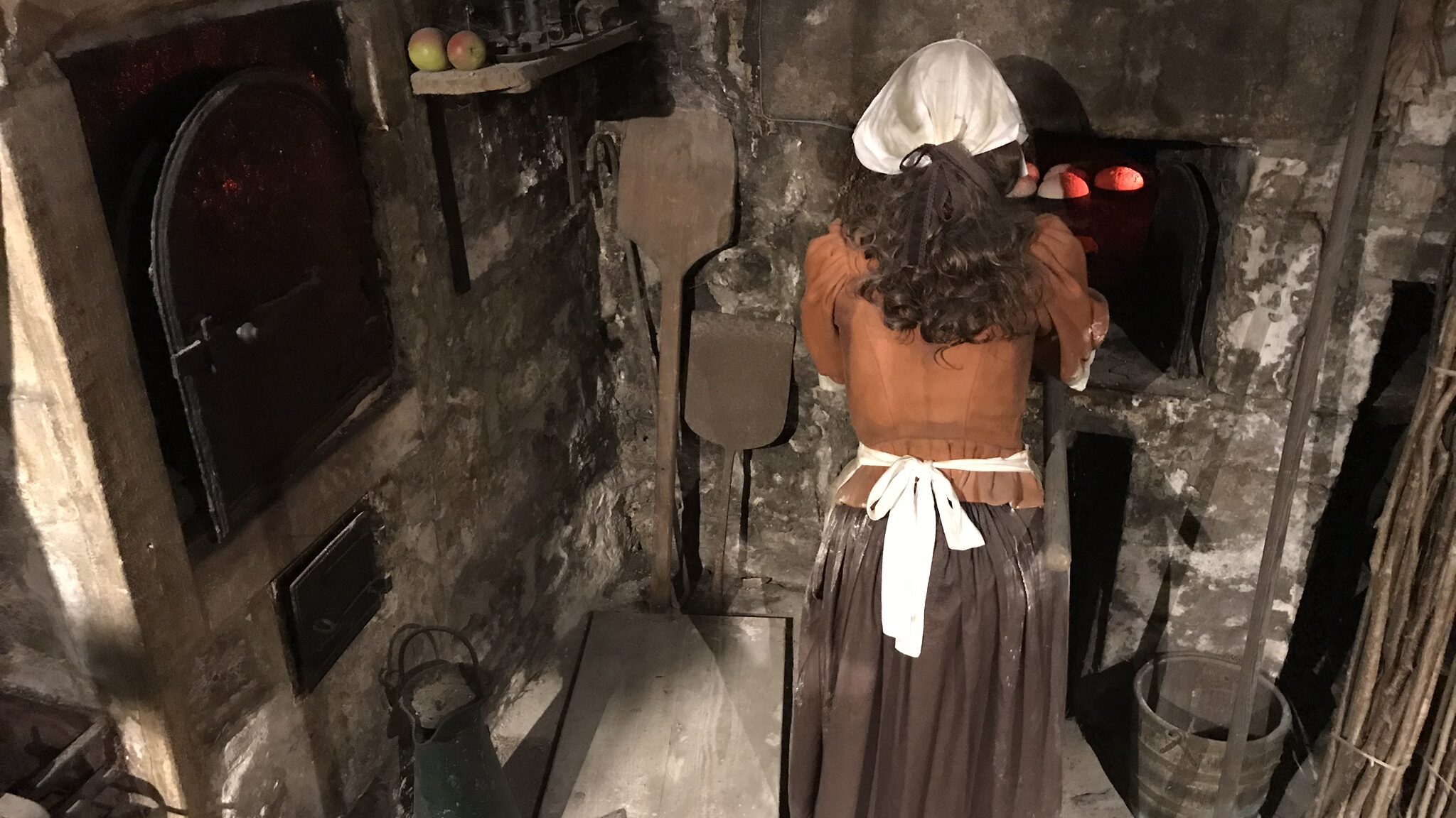 Mannequin of woman putting bread in oven in Bath.