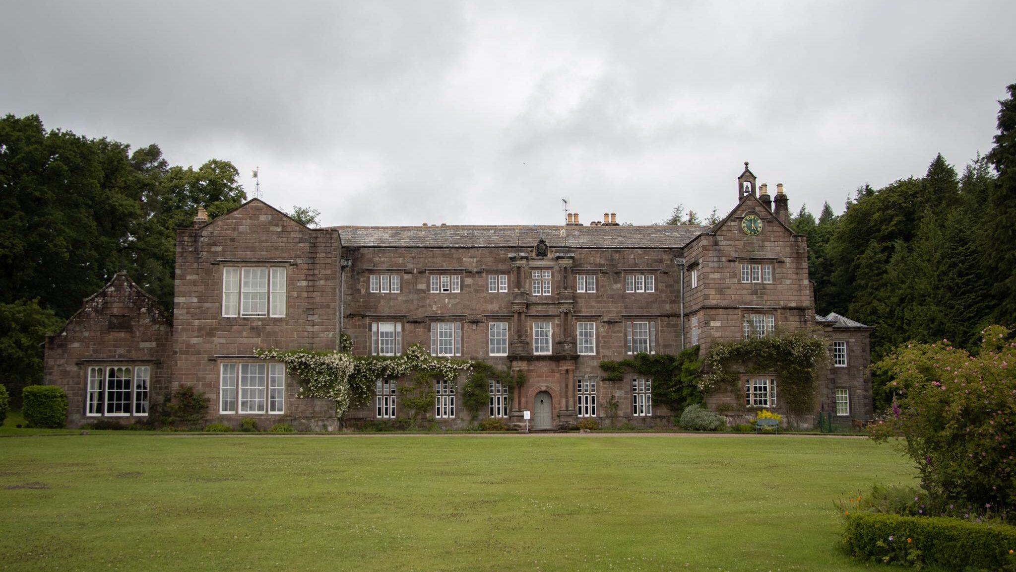 Large historic hall in countryside in England.