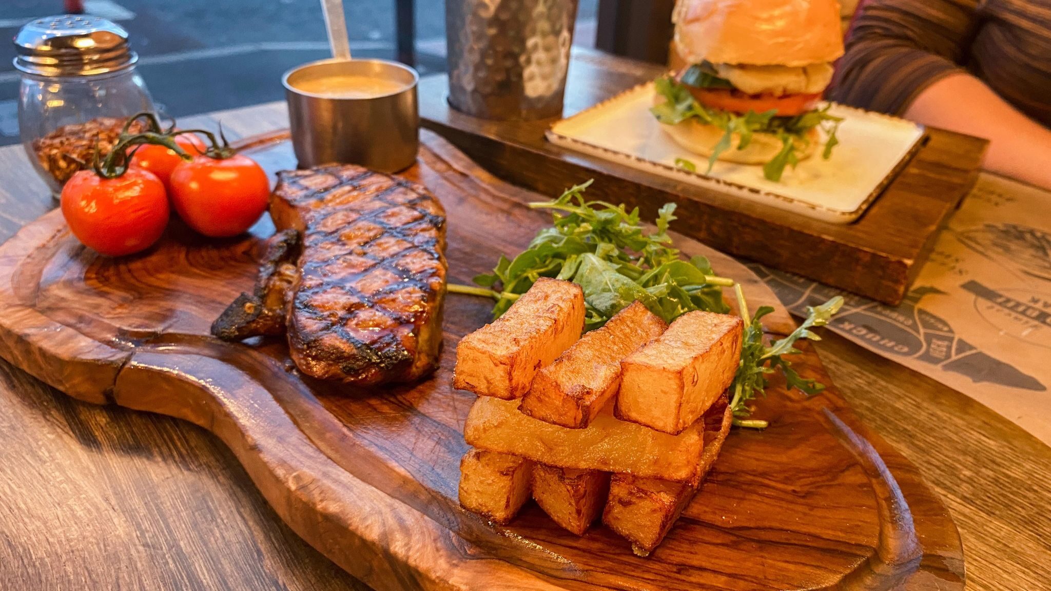 Steak and chips served on wooden board.