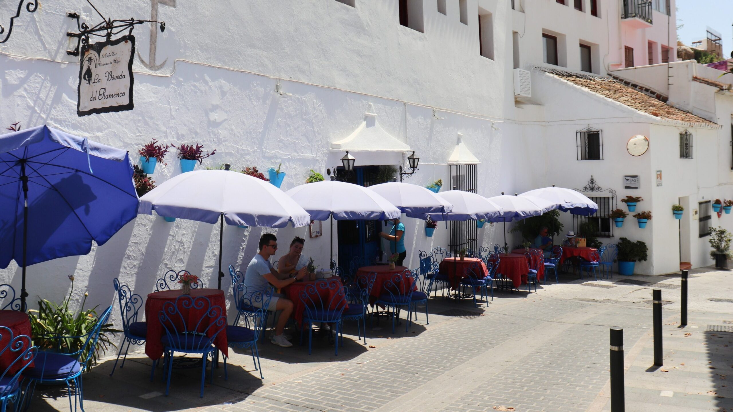 Cafe in village with blue flower pots outside.