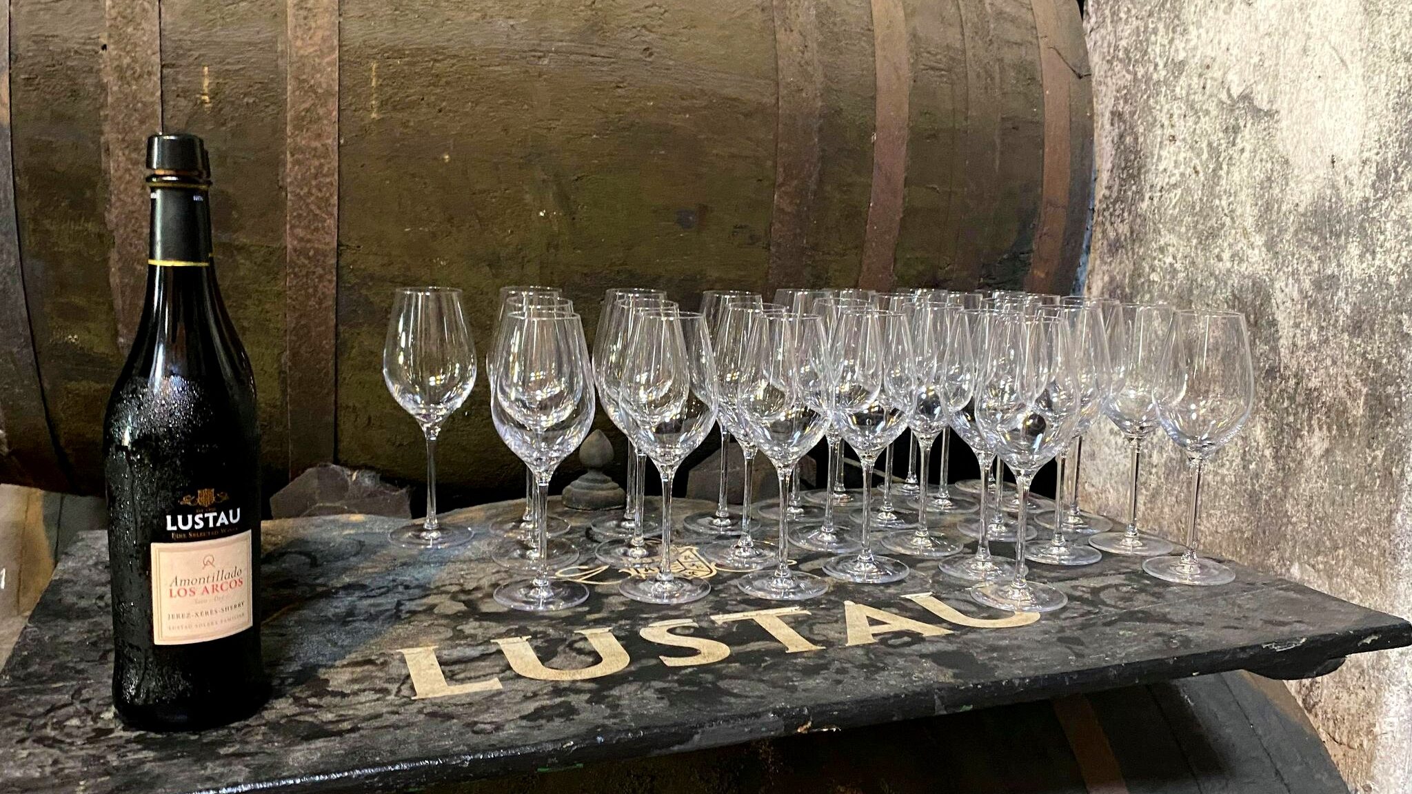 Row of wine glasses next to sherry cask.