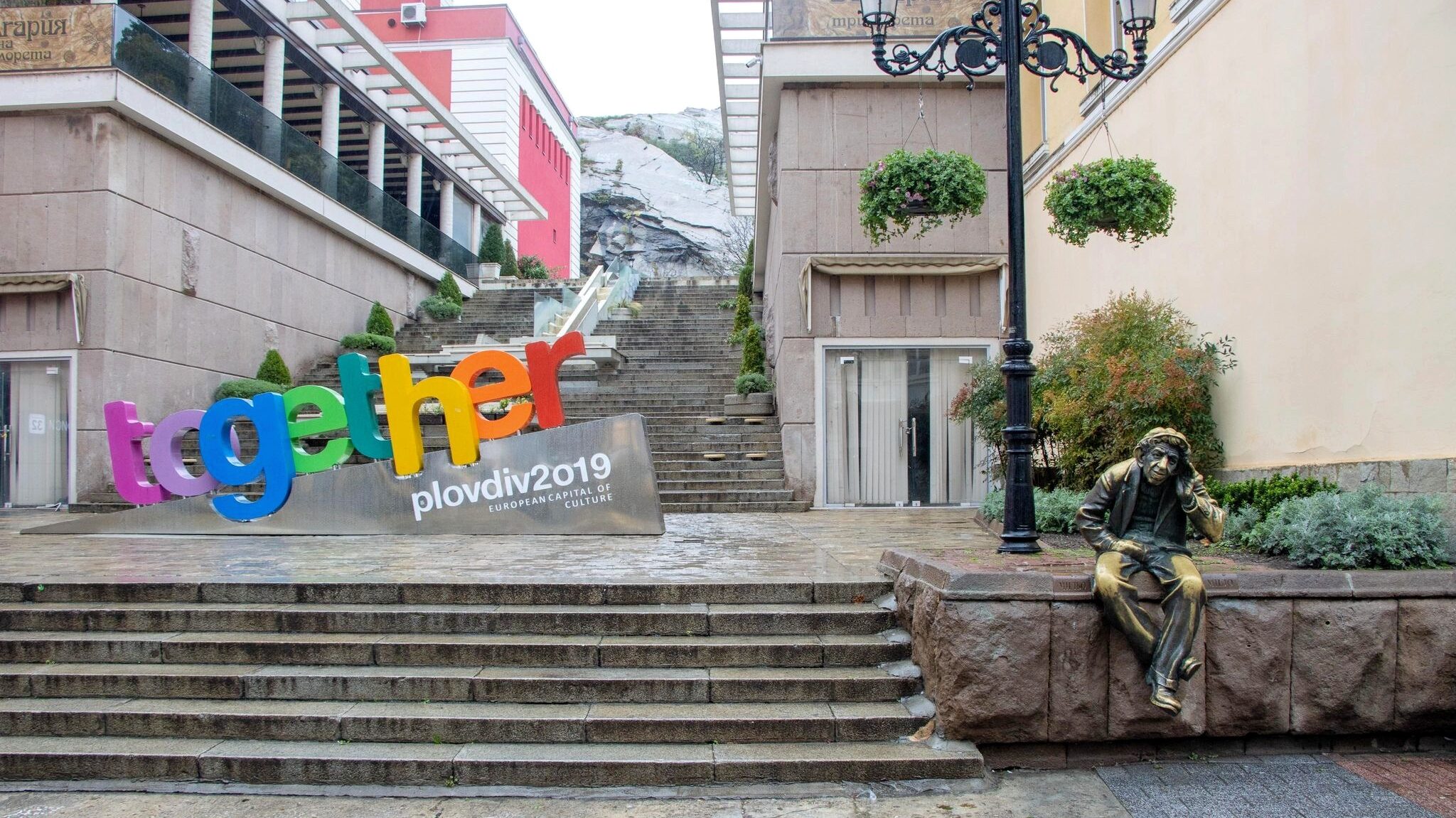 Statue of listening man and colourful Plovdiv sign.