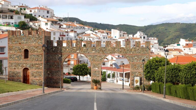 Entrance to white village through brick arches.