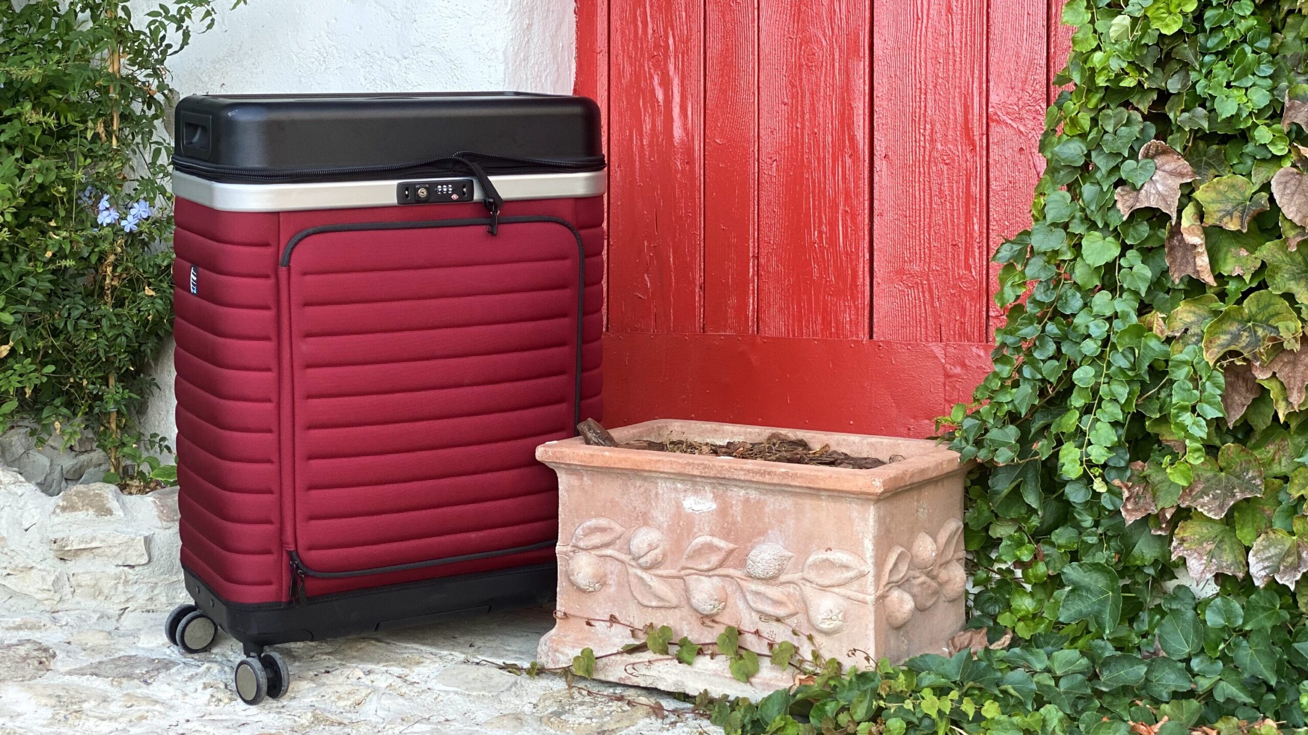 Red and black suitcase next to red door.