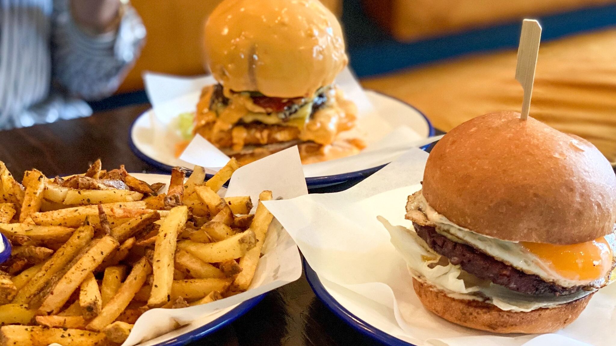 Two burgers and fries on table.