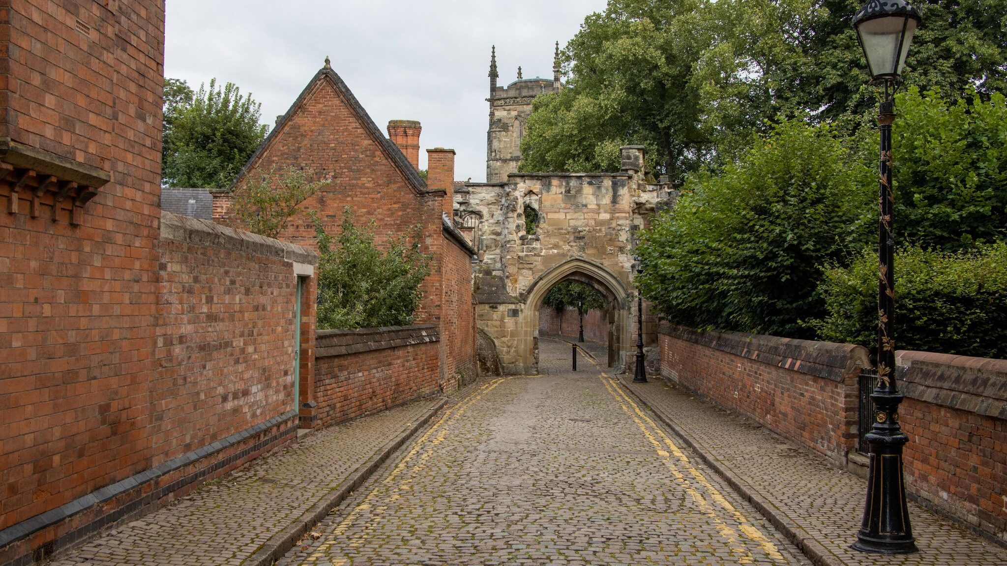 Cobbled street leading to medieval arch. 