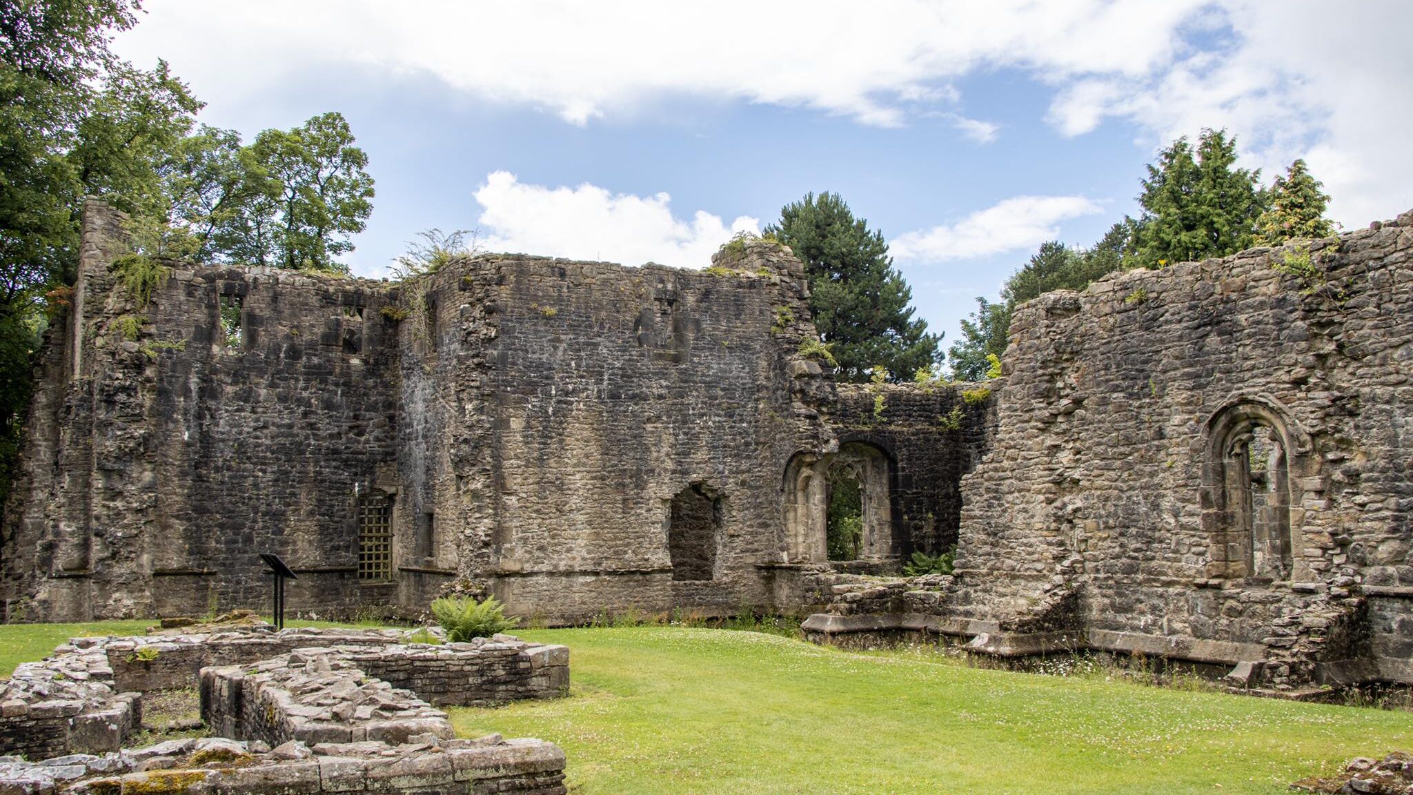 Ruins of a medieval abbey in field.