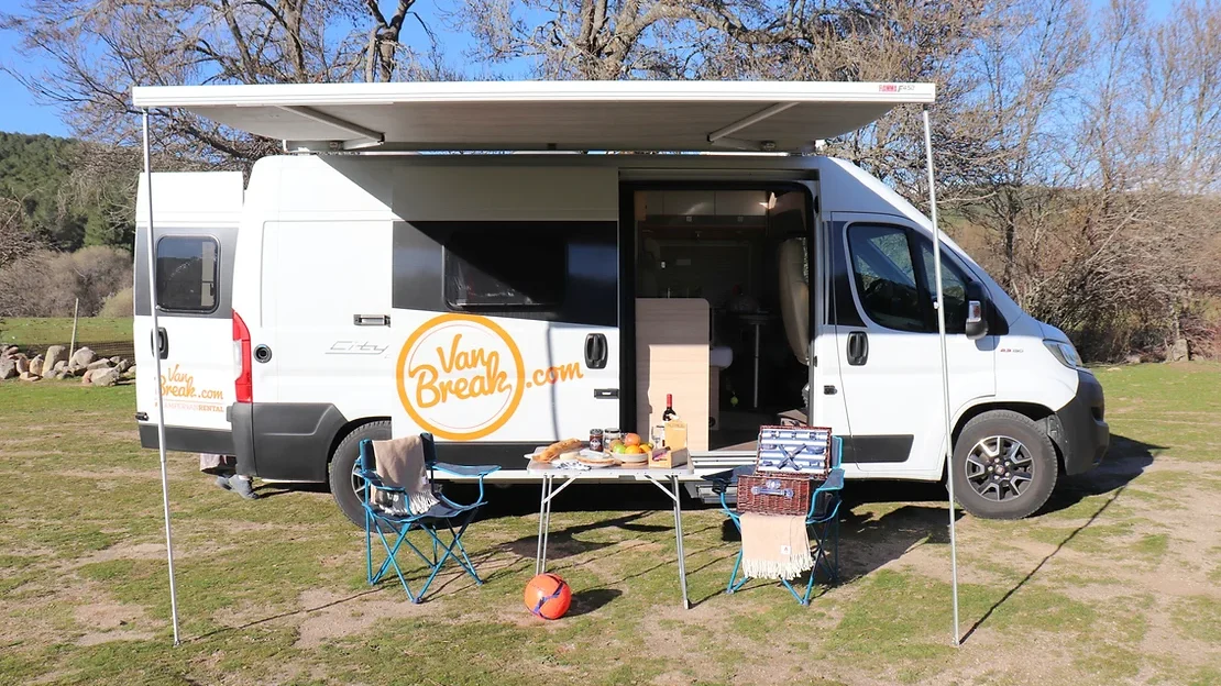 Camper van set up with table outside.