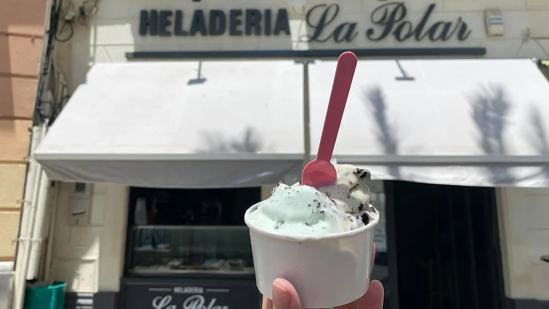 Ice cream cup held up in front of shop.