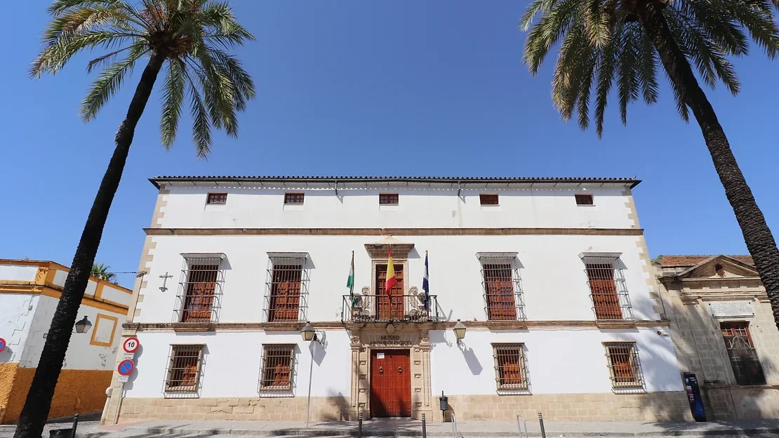 White painted building with palm trees outside.