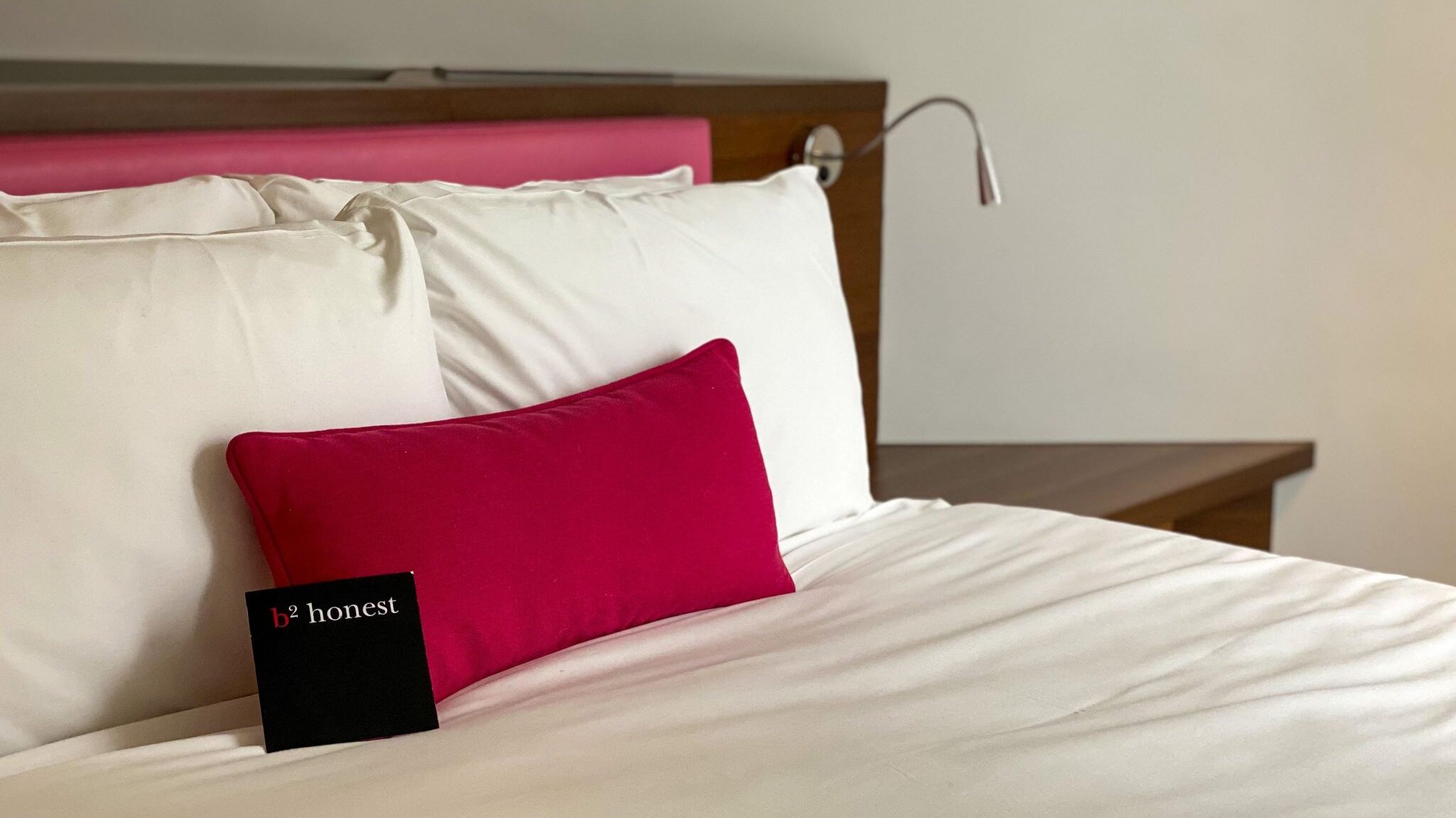 Double bed in hotel room with red pillows.