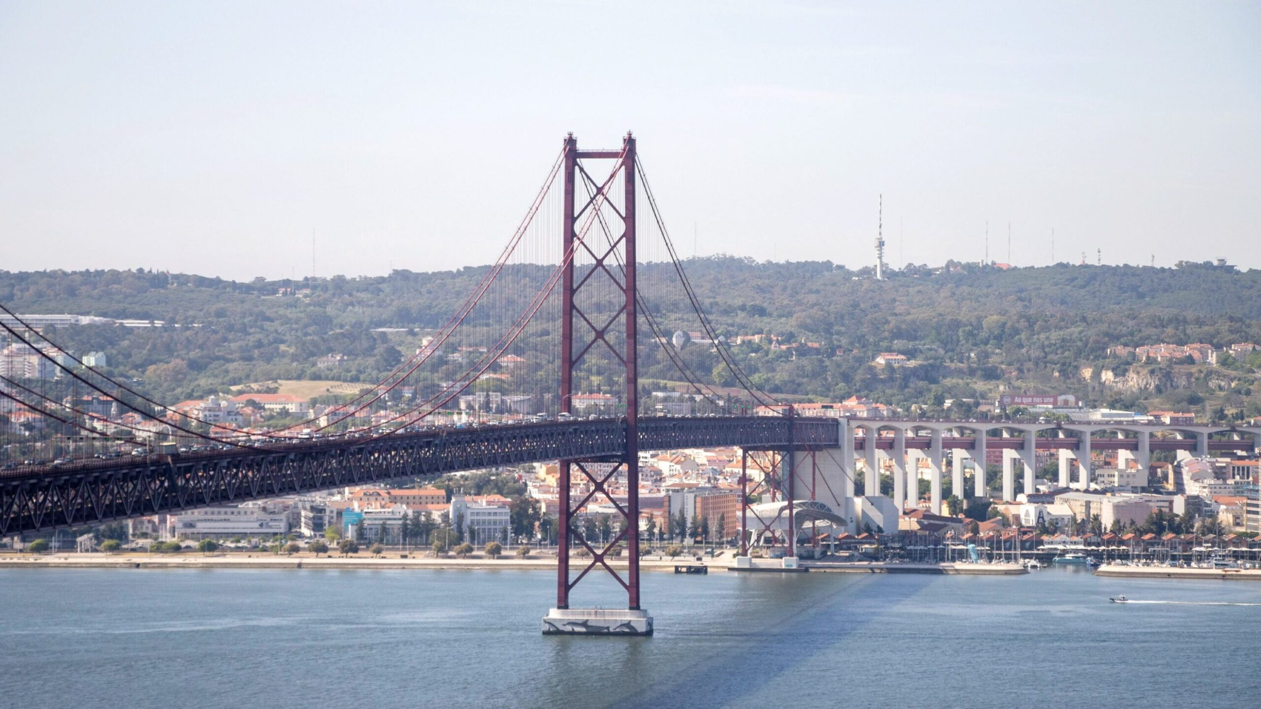 Long red iron bridge crossing river in Lisbon.