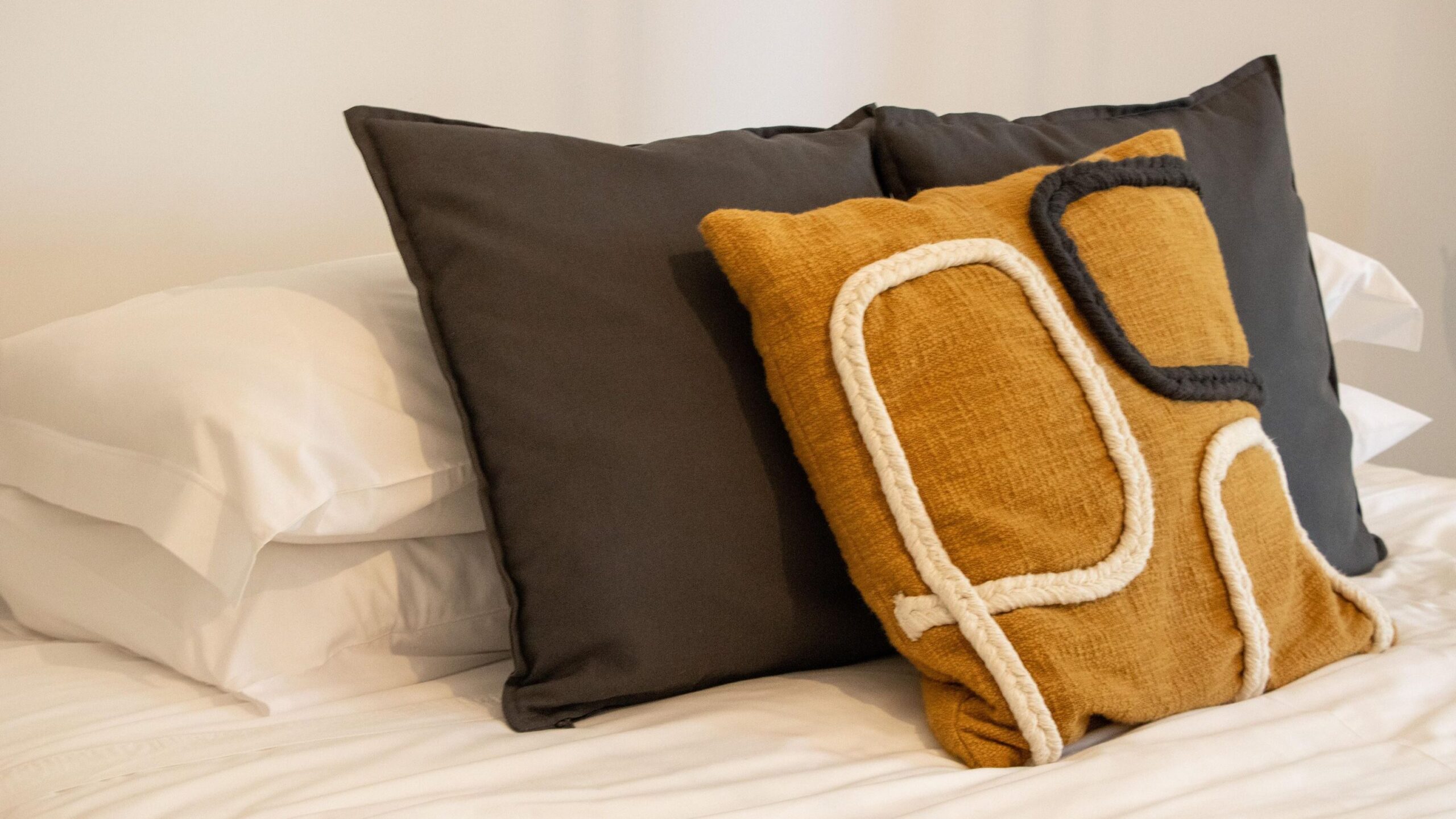 Double bed with yellow and brown decorative pillows. 