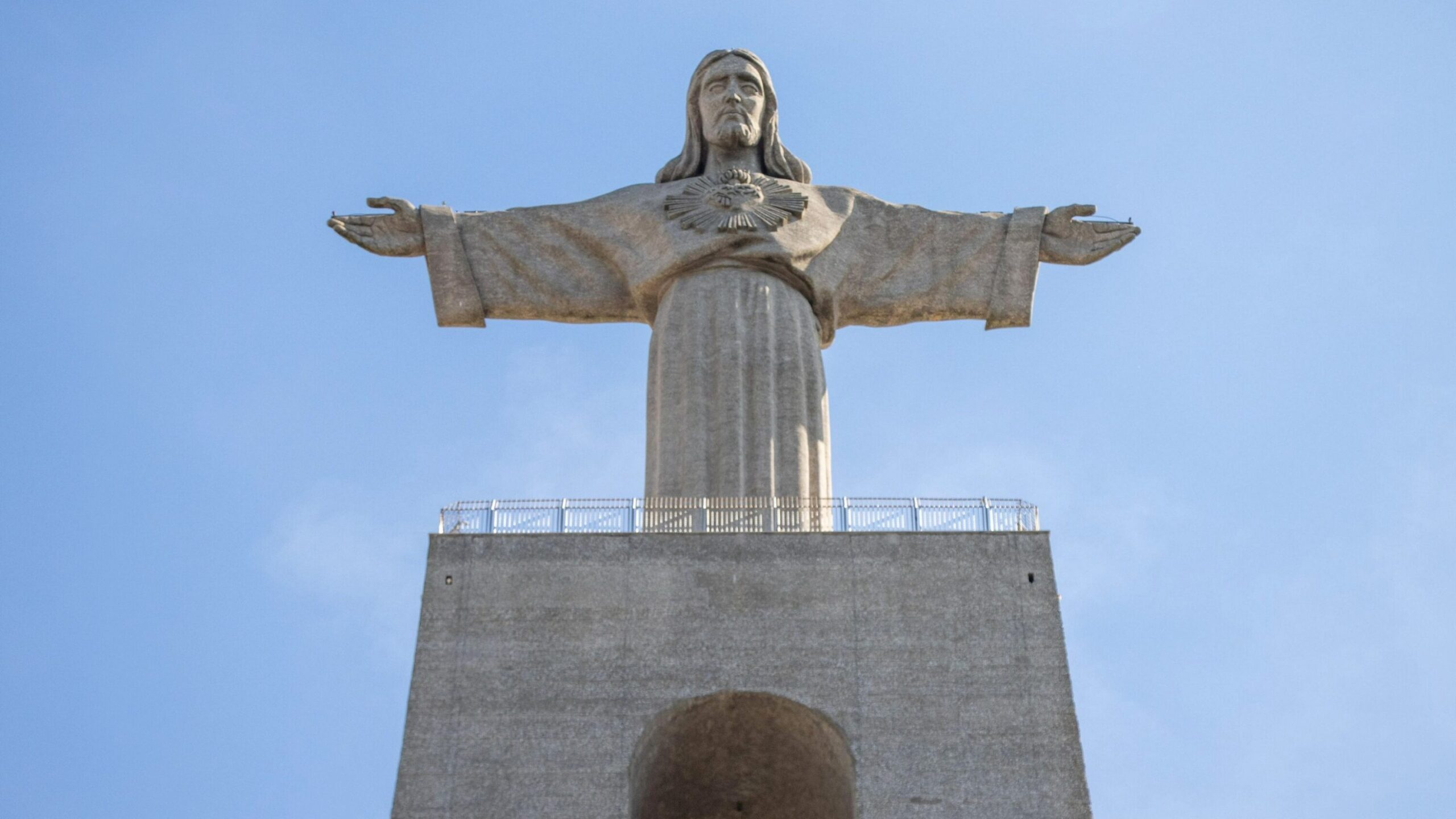 Large statue of Jesus on top of stone structure. 