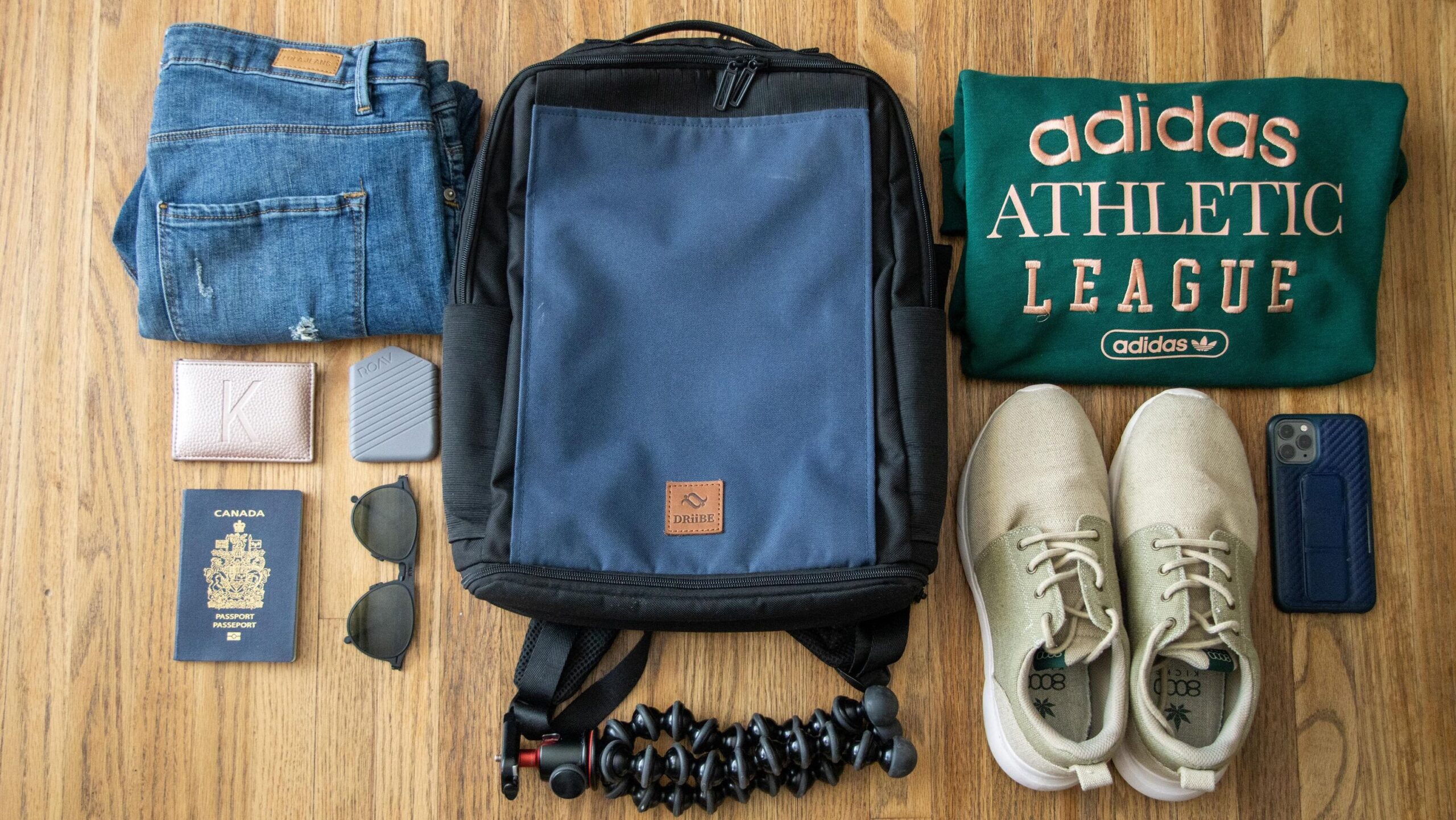 Blue and black backpack with clothes next to it.