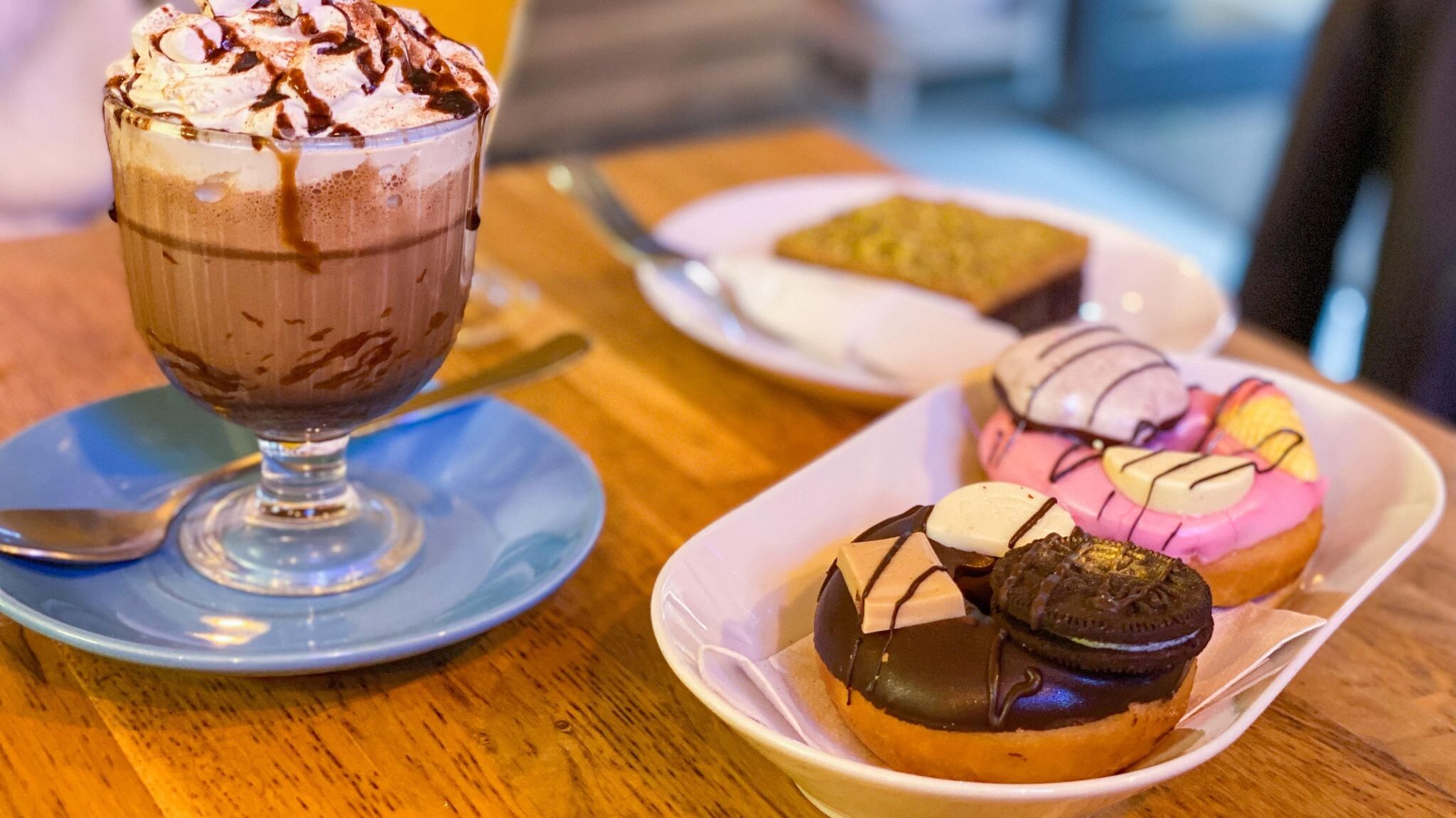 Two doughnuts next to fancy hot chocolate.