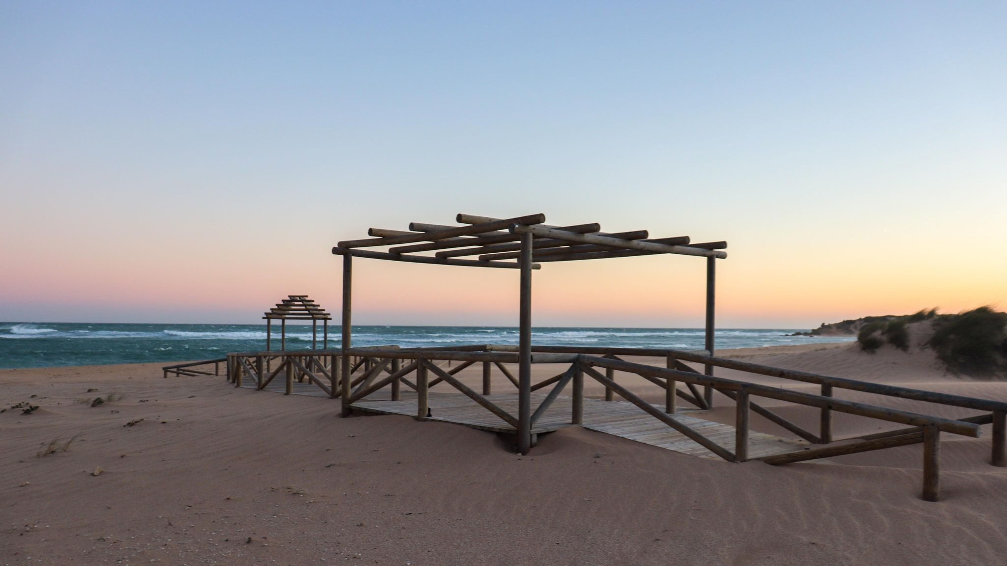 Boardwalk leading to beach at sunset.