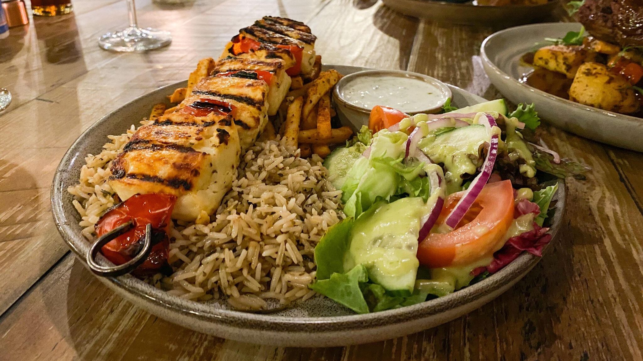 Chicken skewer served with rice and salad.