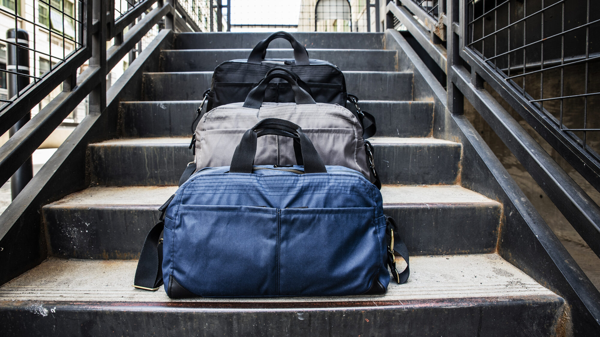 3 duffle bags lined up on steps.