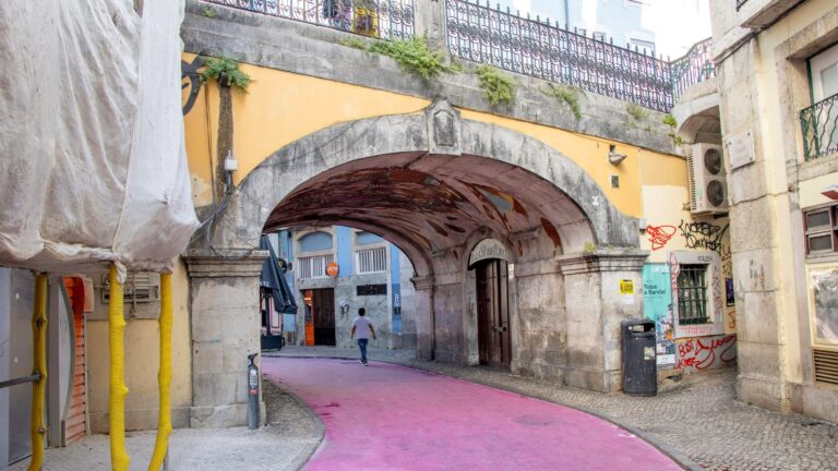 Street painted pink leading under bridge.