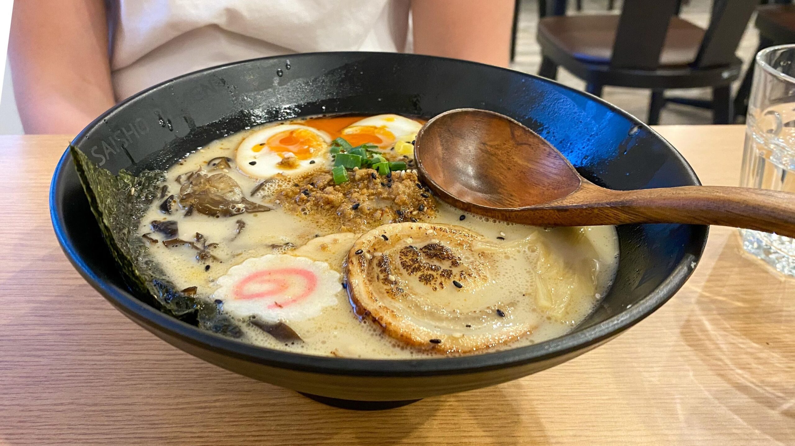 Large bowl of ramen with wooden spoon.