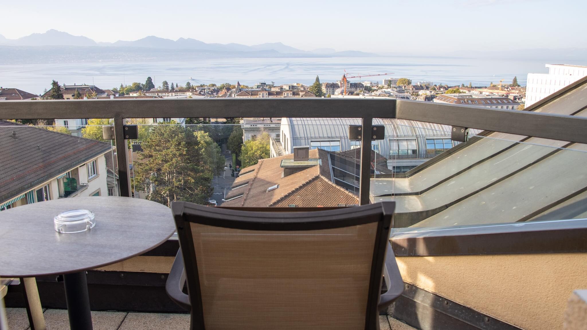 Table and chair on balcony overlooking Lake Geneva is Lausanne worth visiting.