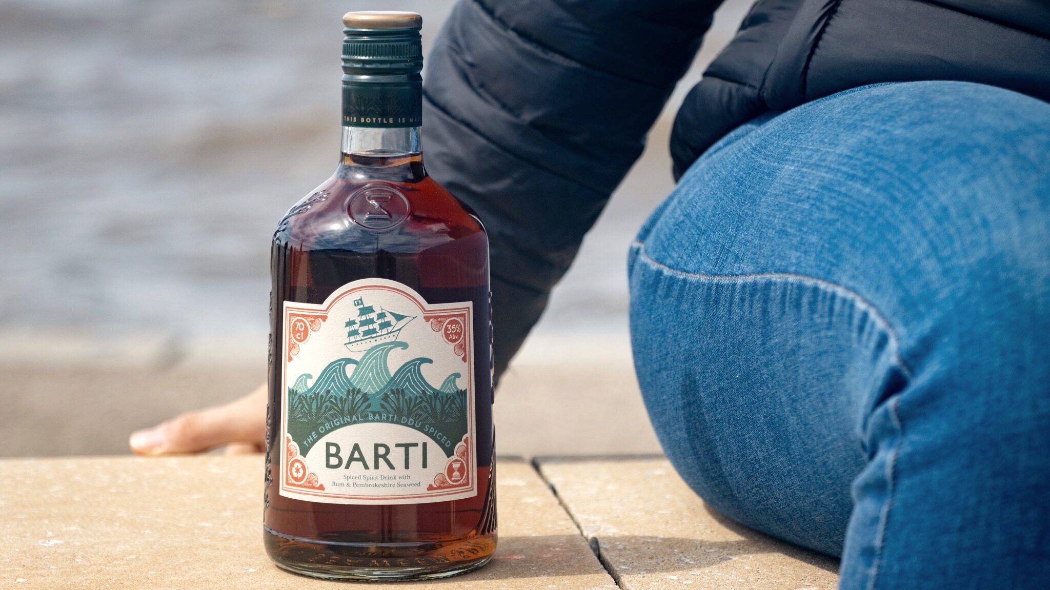 Bottle of rum on promenade next to sea.