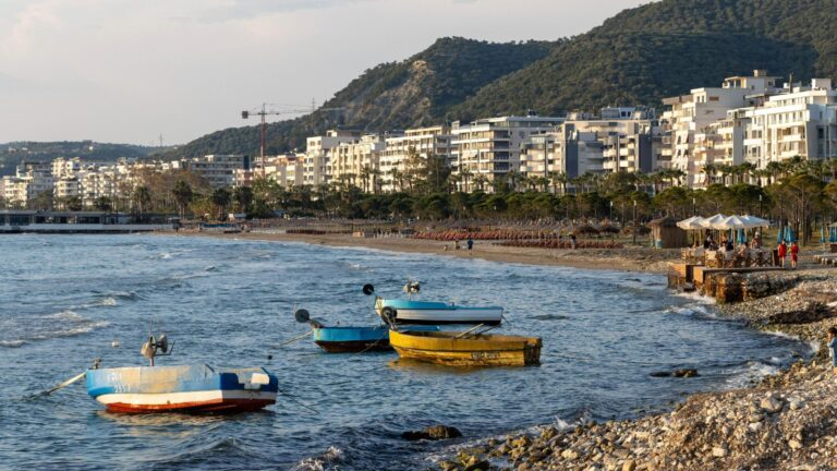 Beach in Vlore with fishing boats in water.