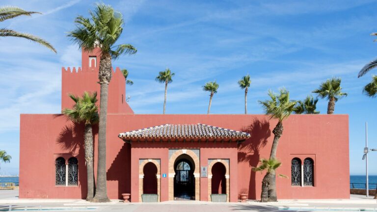 Red painted modern castle along waterfront.