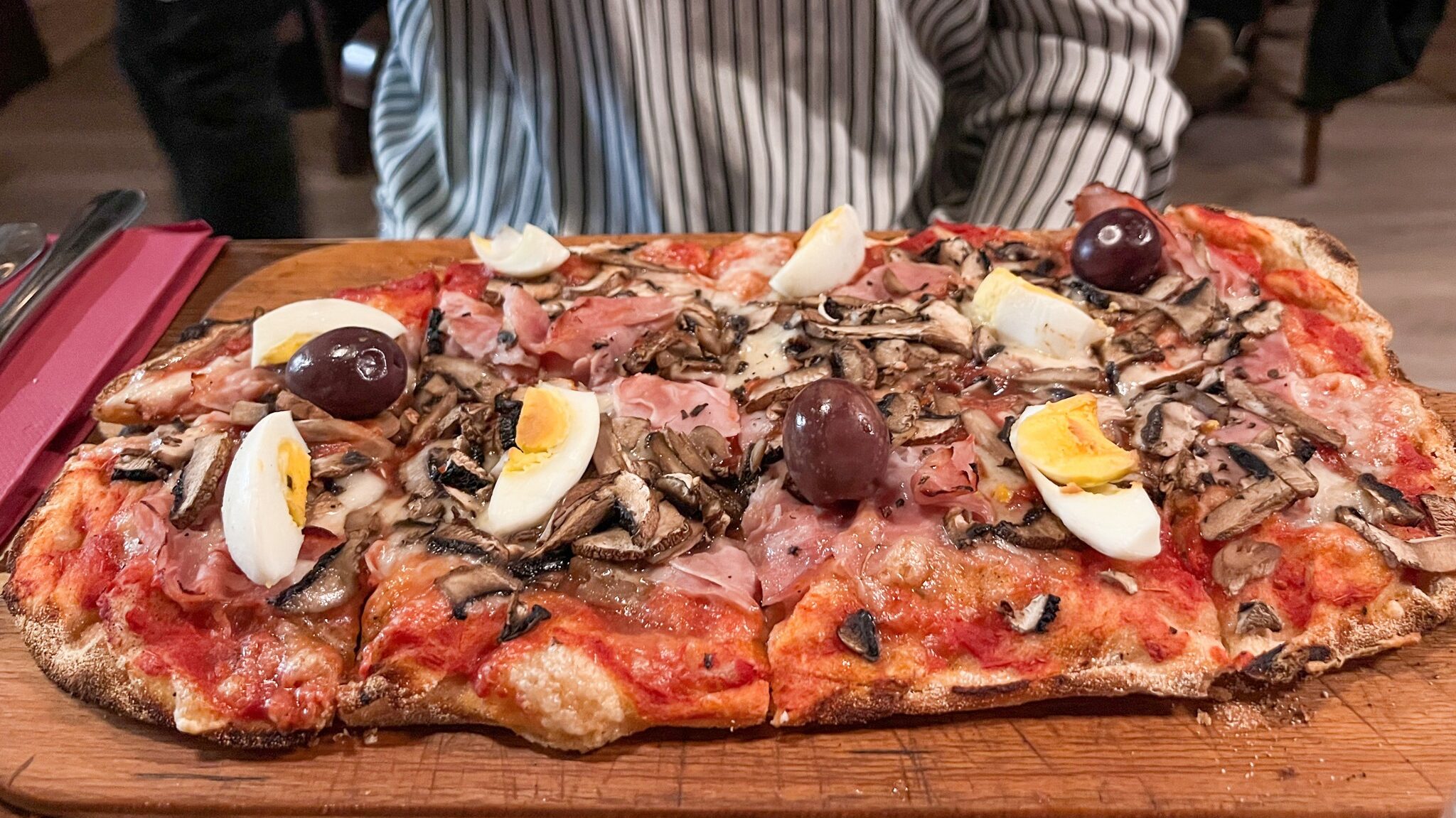 Pinsa style pizza with boiled eggs on top.