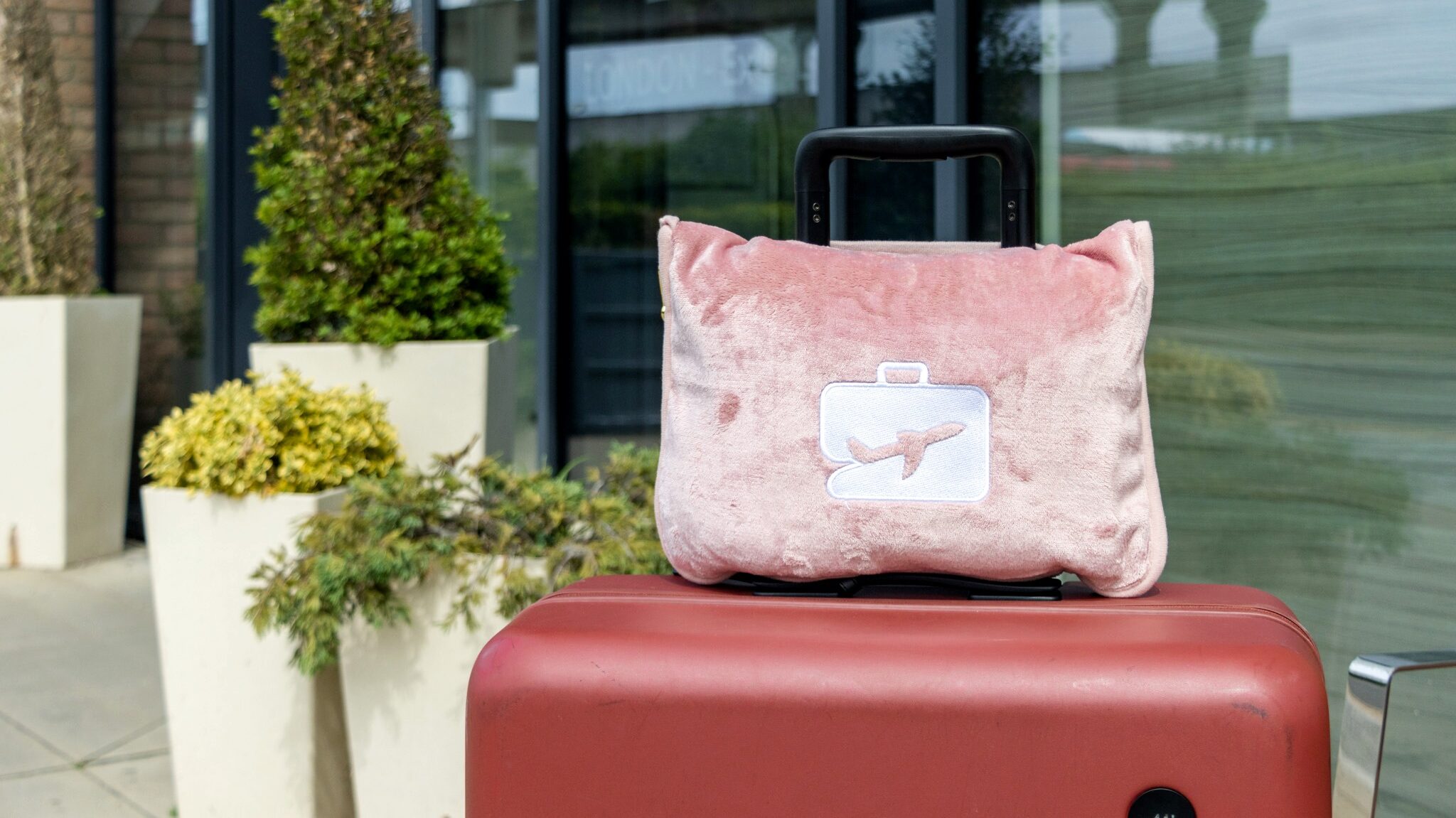 Pink travel pillow on top of suitcase.