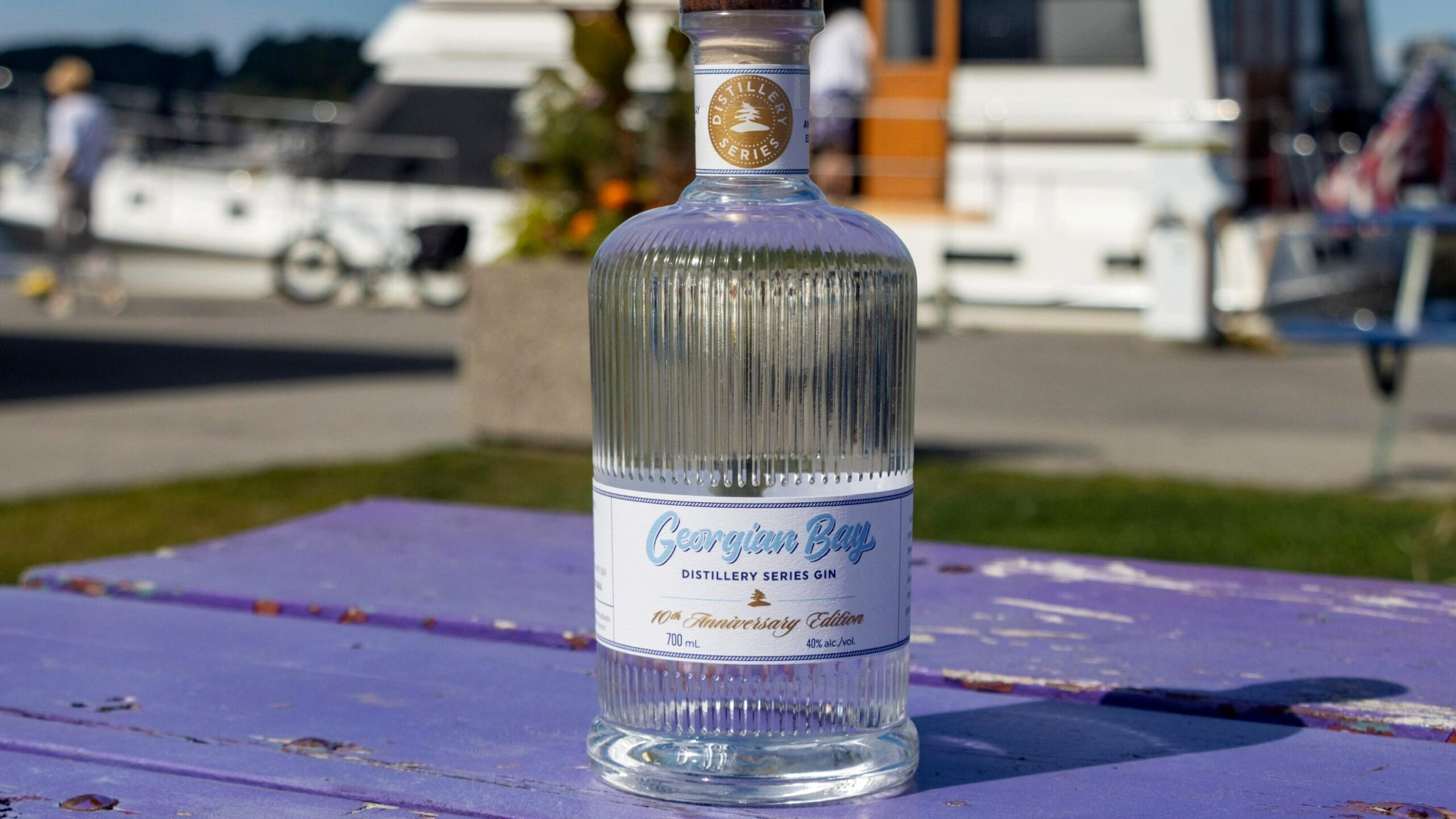 Bottle of Canadian gin on purple bench.