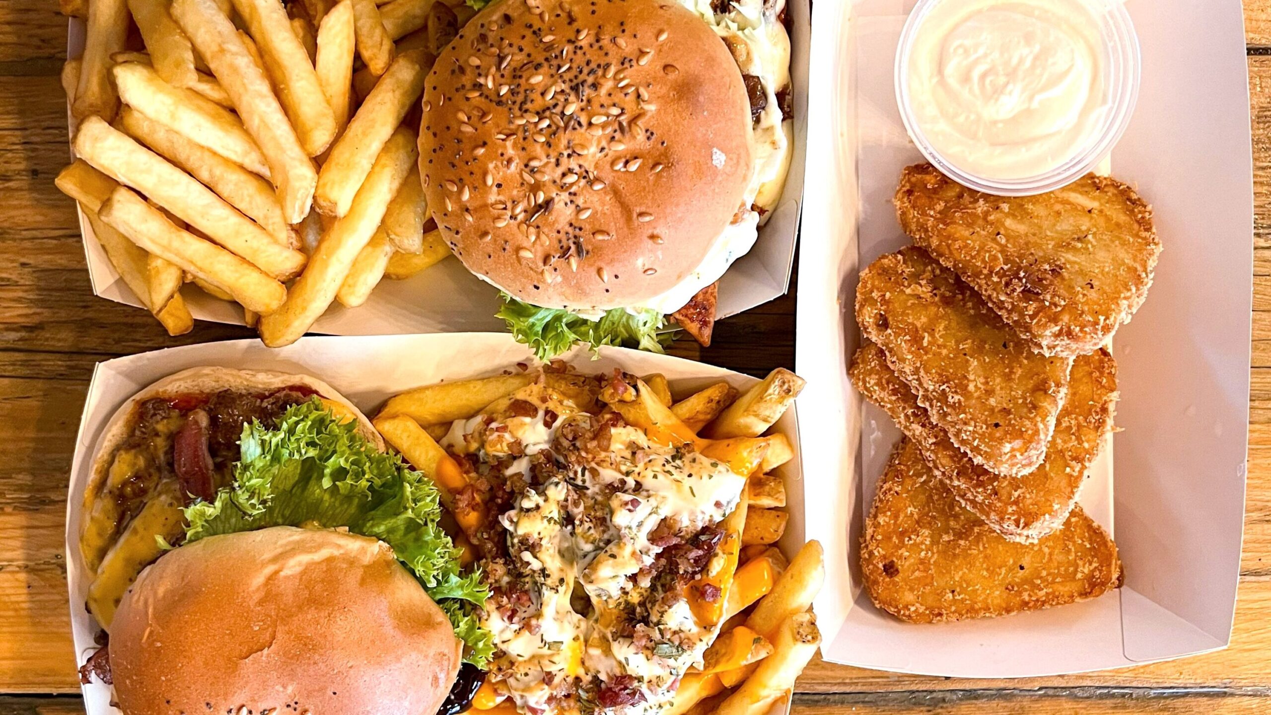 Flat lay of burgers with fries and hash browns.