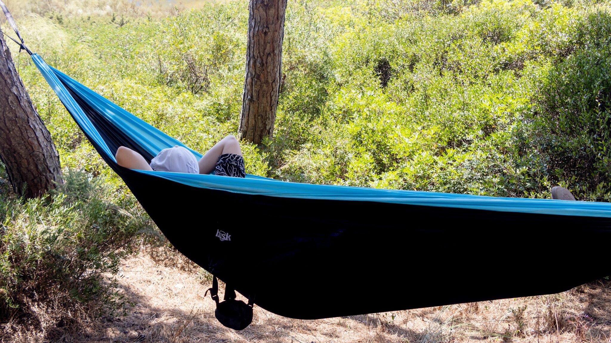 Person inside black and blue hammock.