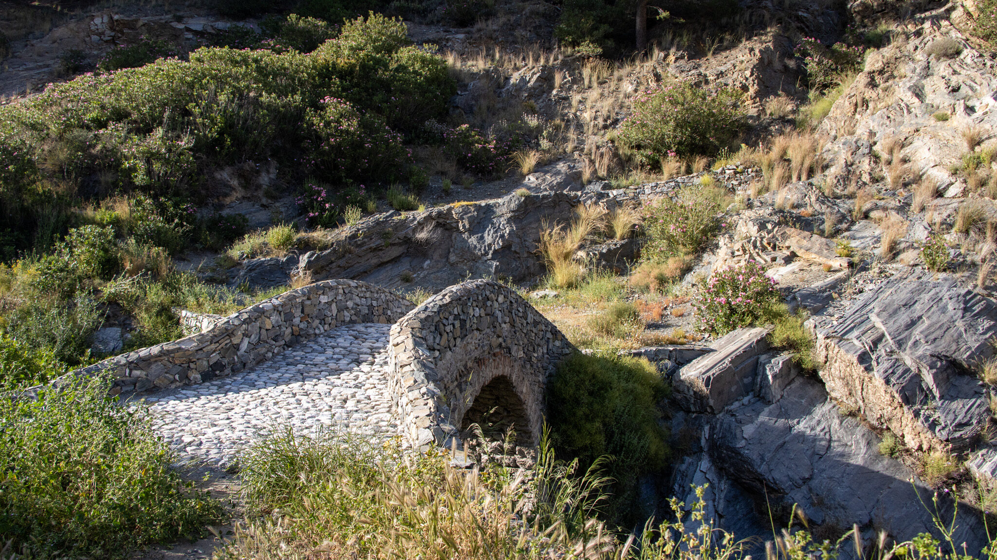 Small stone Roman bridge on hiking trail.