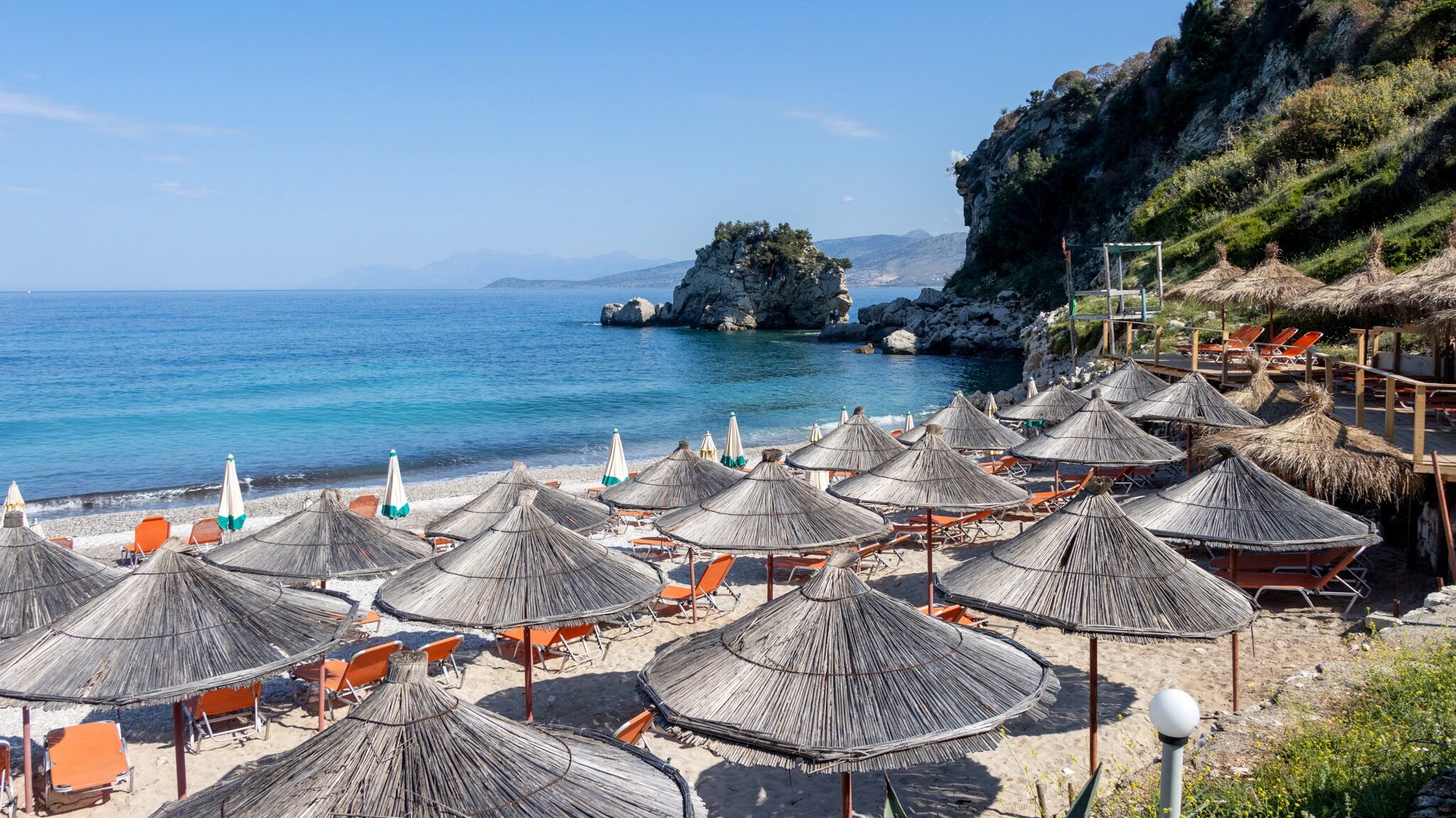 Small beach in Albania with sun beds.