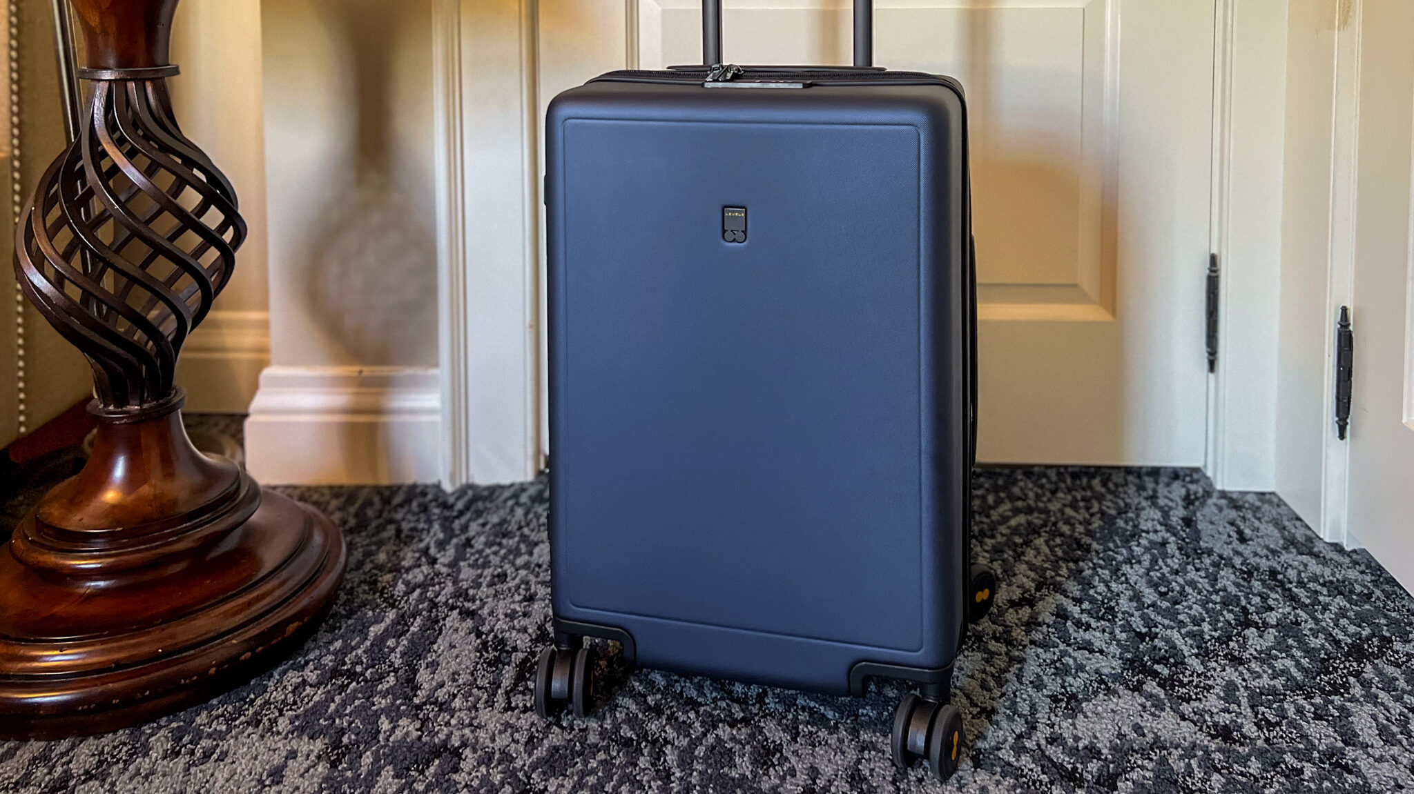 Dark blue hard shell suitcase in hotel room.