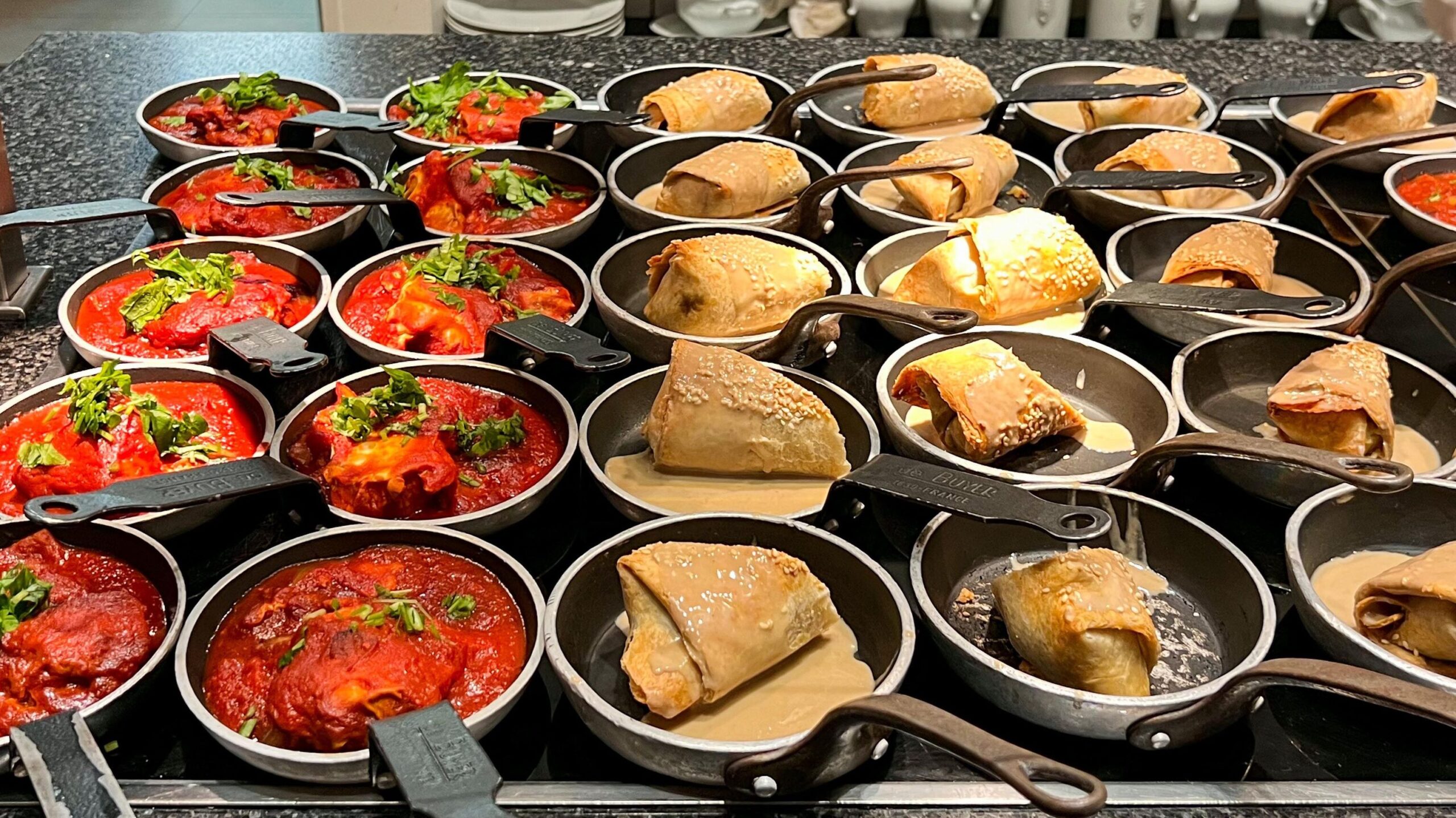 Row of mini iron dishes with breakfast food.