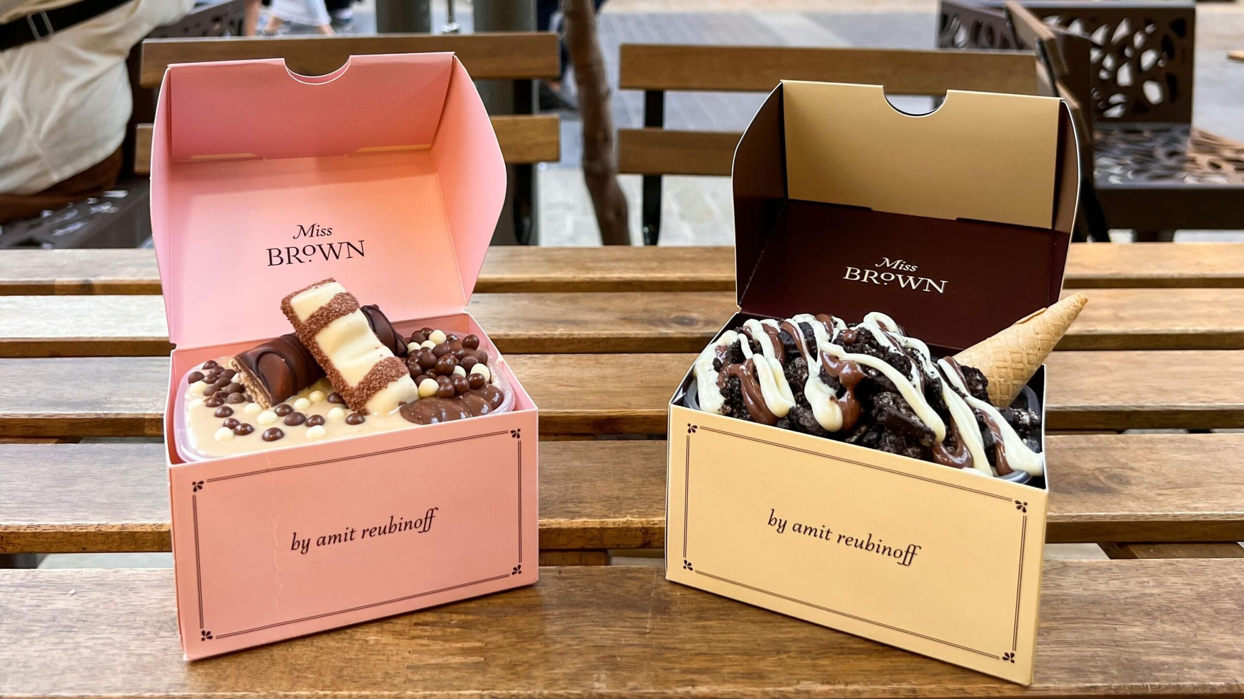 Two desserts in boxes on table.