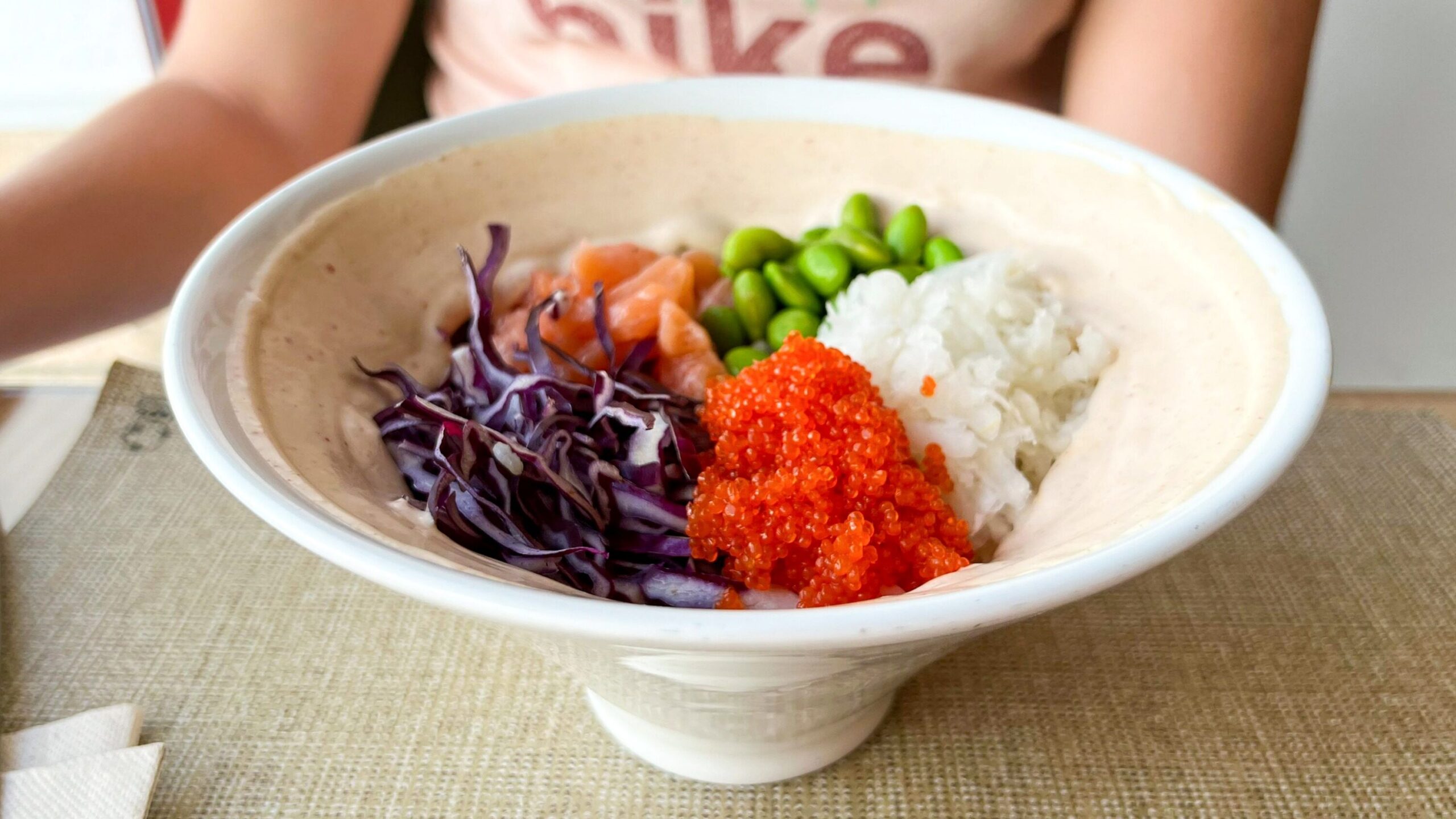 Tall poke bowl with fresh vegetables. 