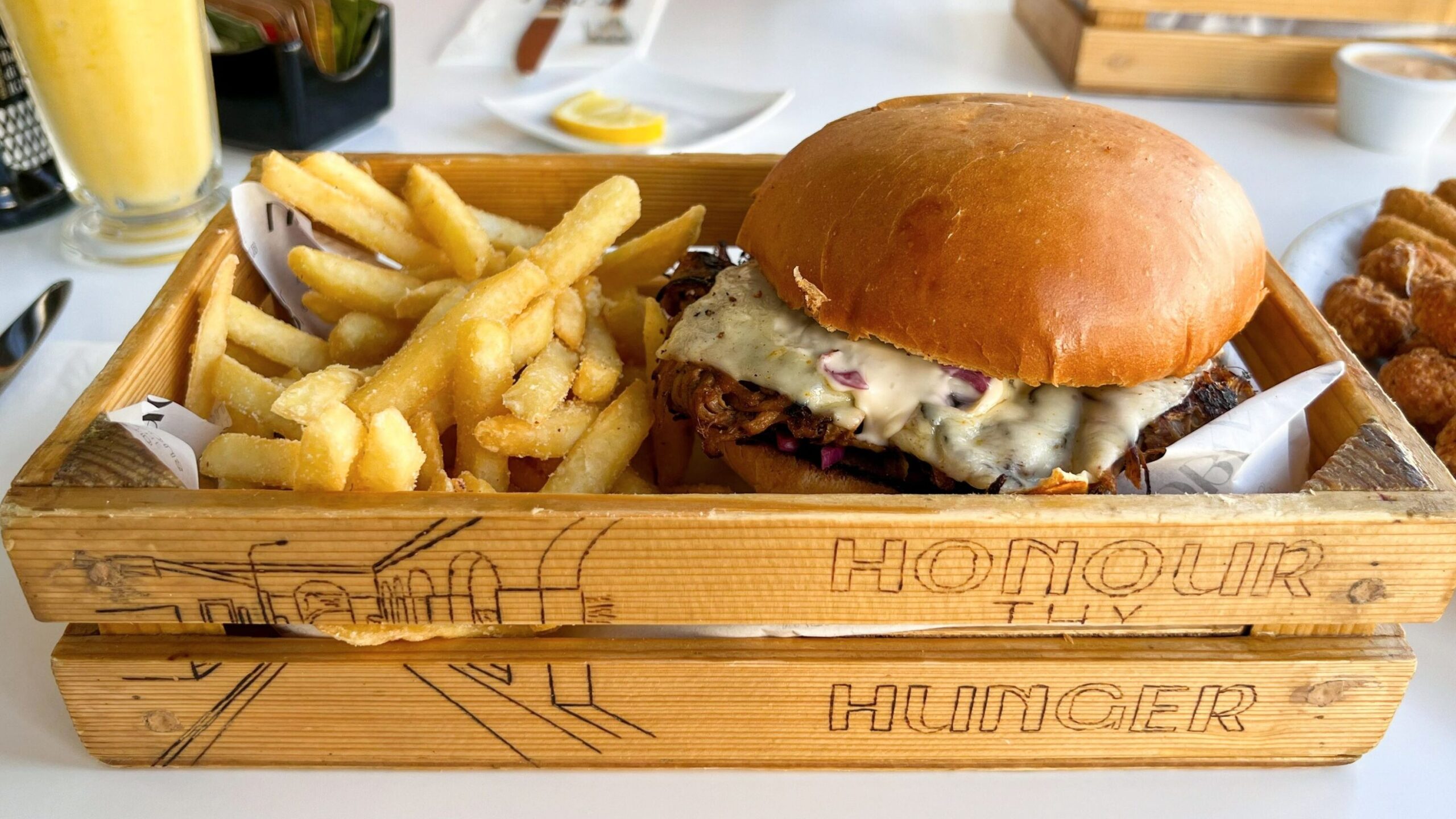 Cheesy burger with fries in wooden box.