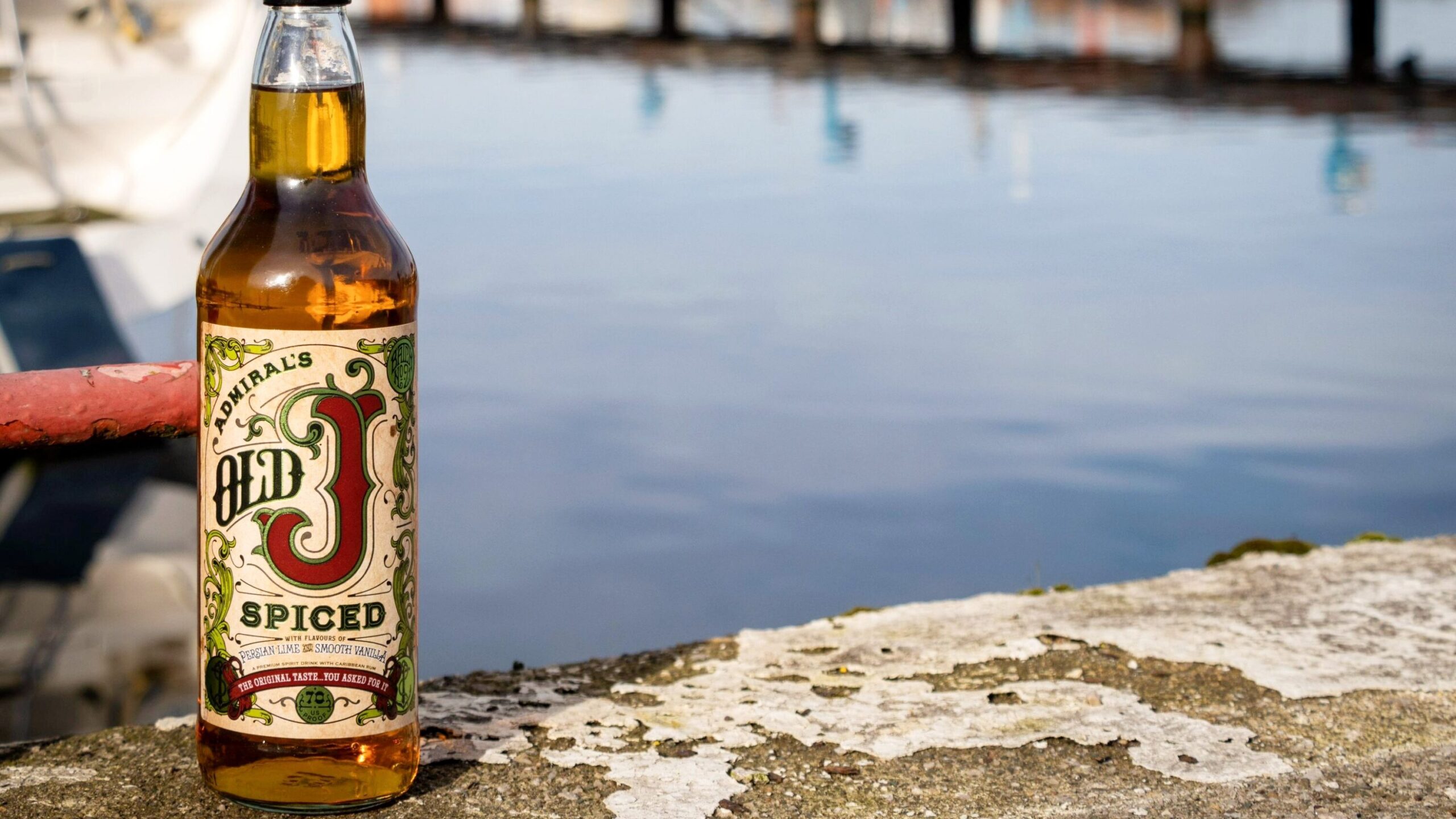 Bottle of rum sitting next to harbour.