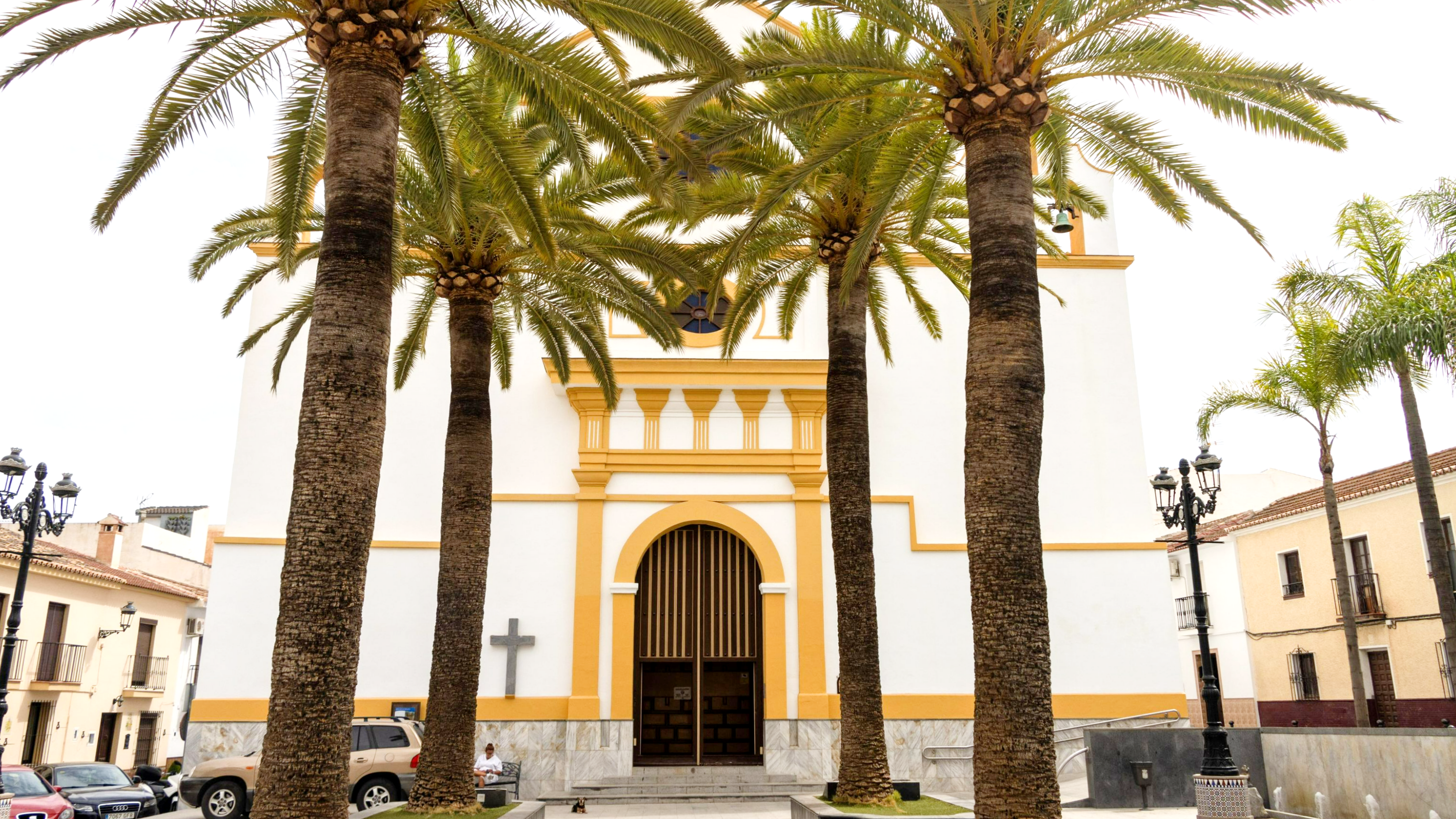 White and yellow painted church with palm trees.