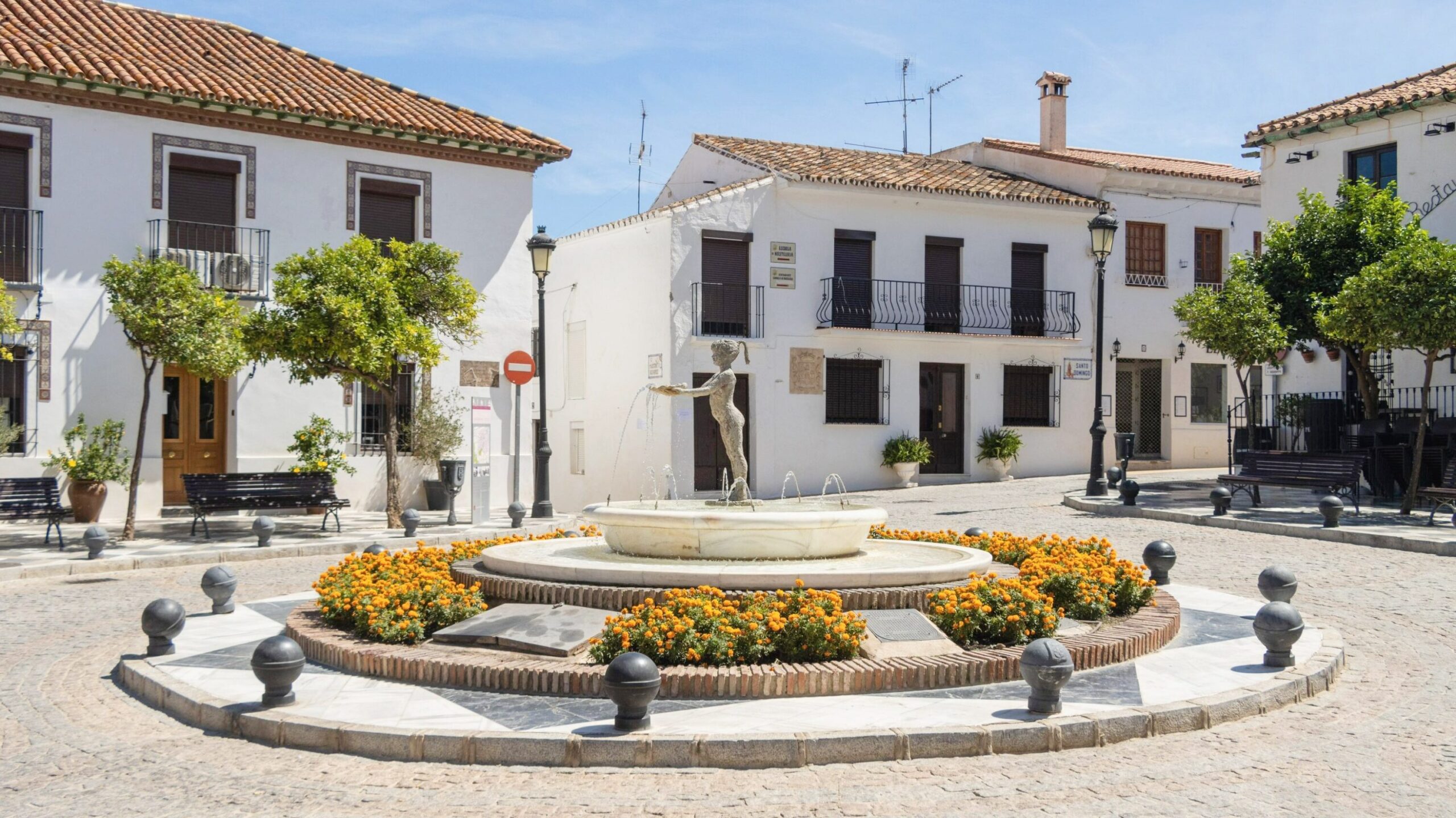 Plaza in white village with water fountain. 